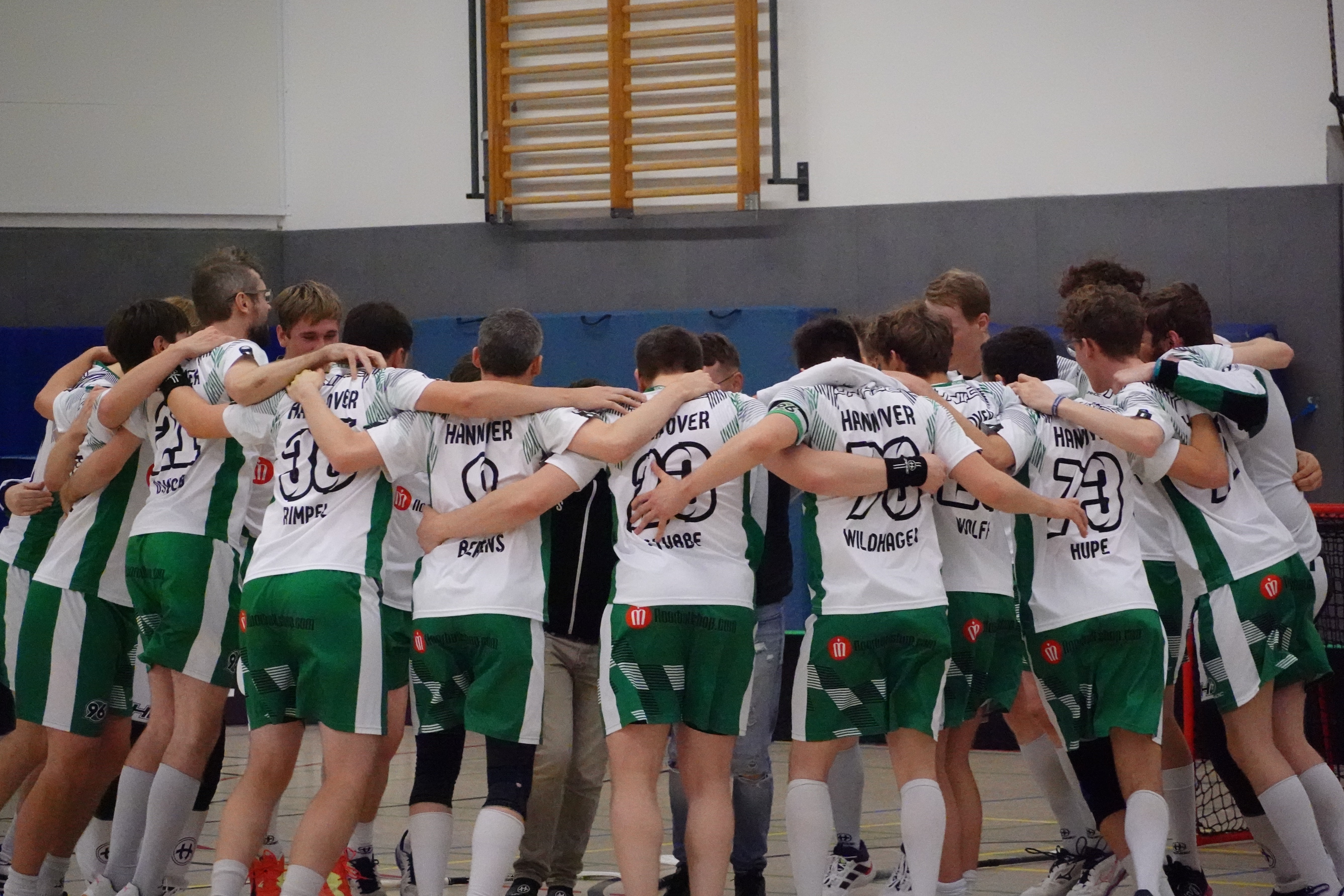 Die Spieler stehen Arm im Arm in einem Kreis.