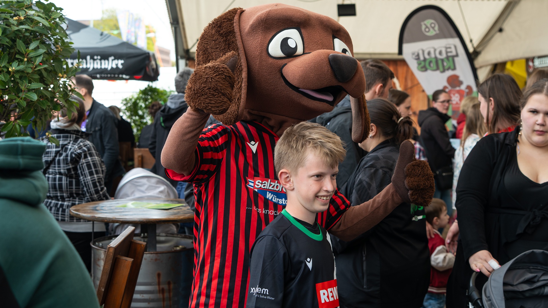 96-Maskottchen EDDI posiert mit einem jungen 96-Fan