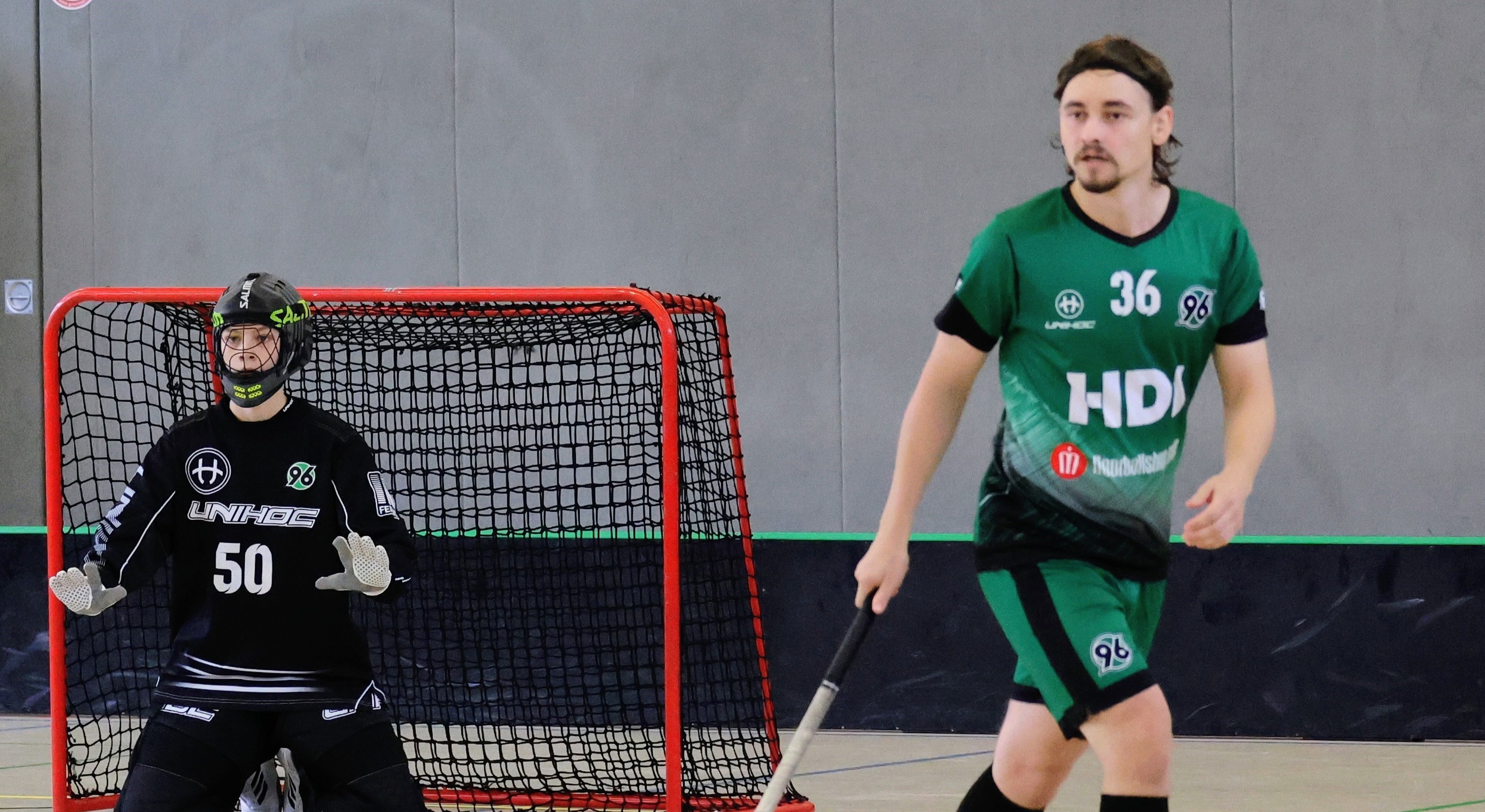 Ein Spieler im grünen Trikot hält einen Schläger in der Hand.