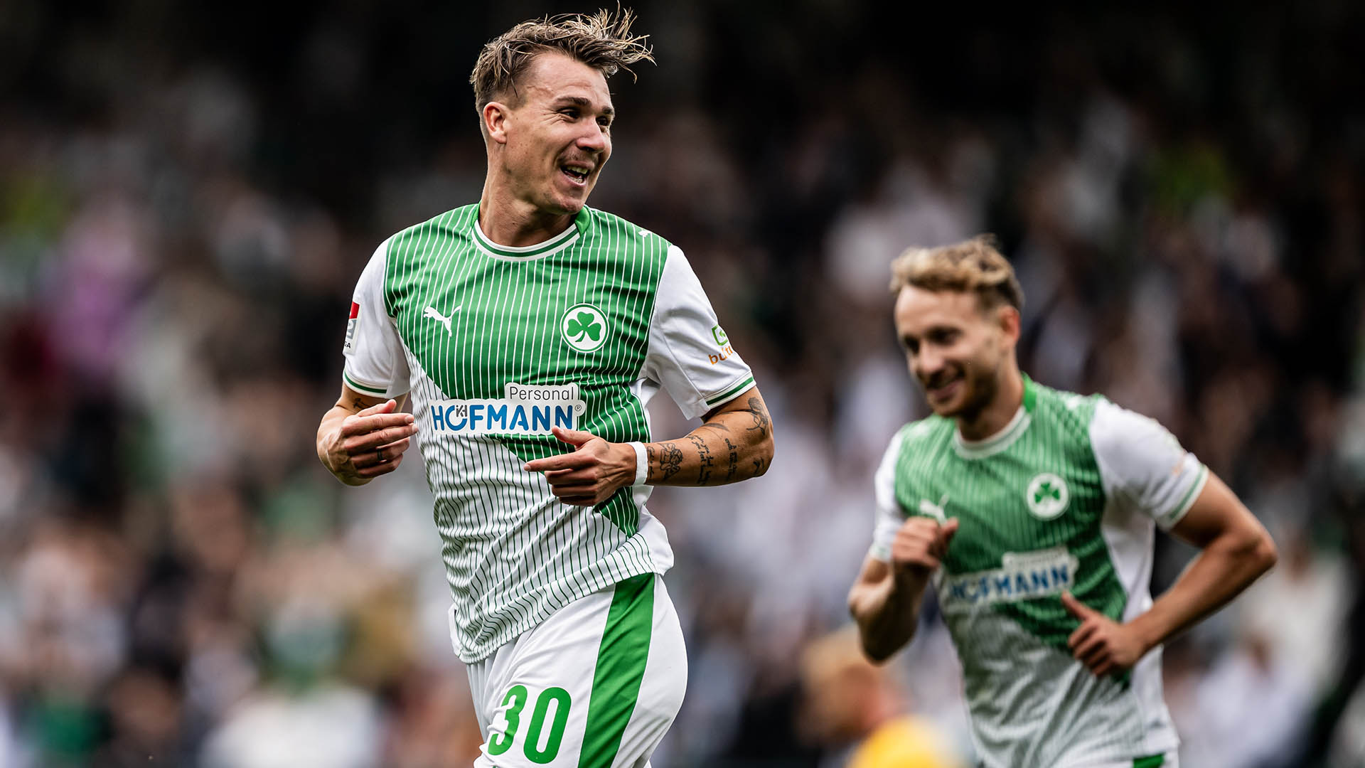 Felix Klaus der lachend über einen Fußballplatz läuft.
