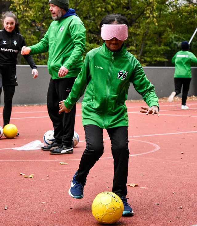 Eine Spielerin dribbelt mit einer Dunkelbrille auf dem Feld.