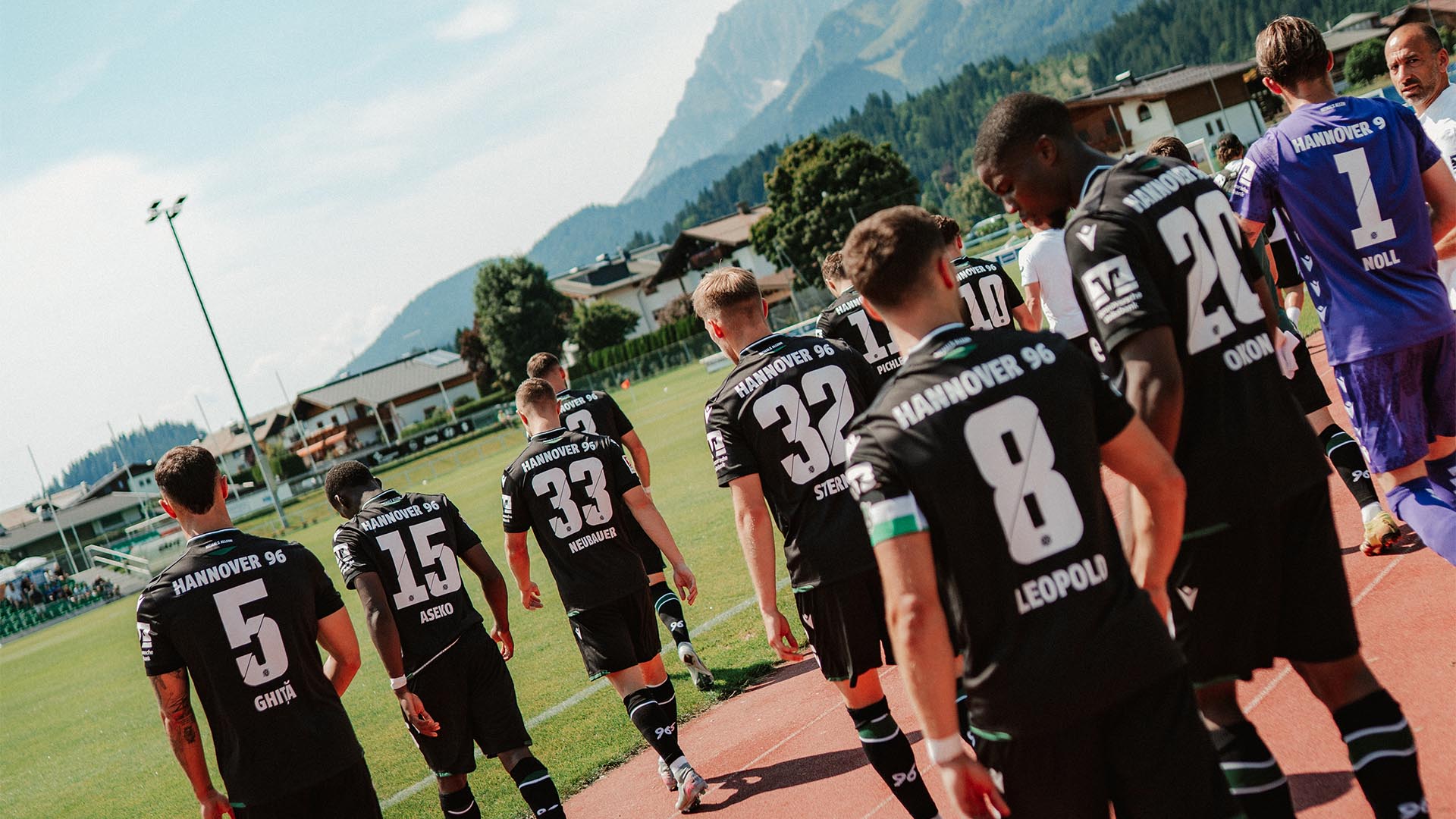 Einige Spieler sind von hinten auf dem Weg zum Platz zu sehen.