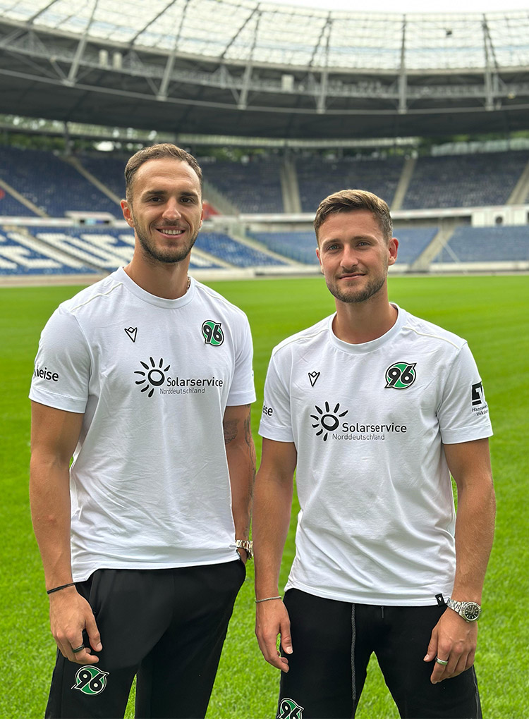 Virgil Ghita und Enzo Leopold stehen in der leeren Heinz von Heiden Arena und lächeln in die Kamera.