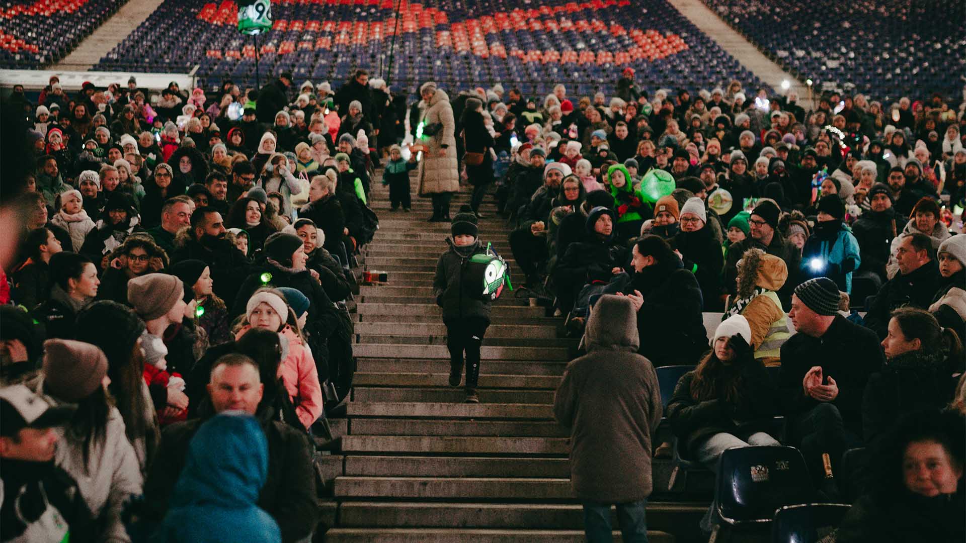 Die Teilnehmenden des Laternenumzugs sitzen im Unterrang der Arena.