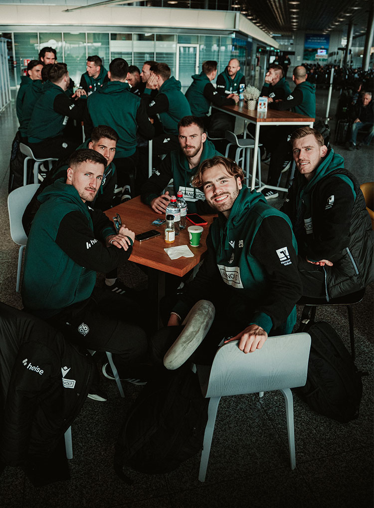 Enzo Leopold, Oudenne, Leo Weinkauf, Boris Tomiak und Franz Roggow sitzen am Flughafen an einem Tisch.