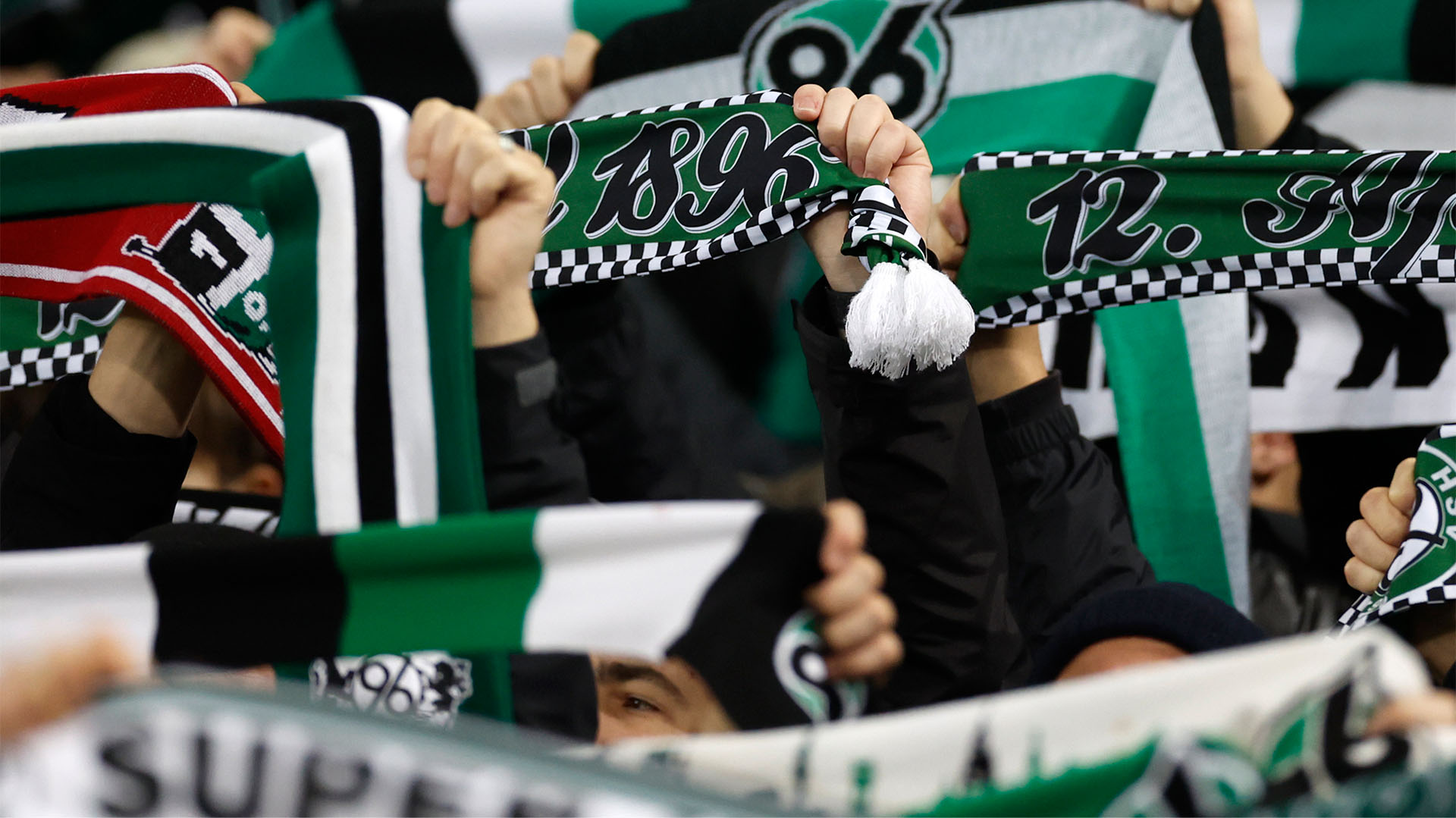 96-Schals werden in die Höhe gehalten, Gesichter sind nicht zu sehen.