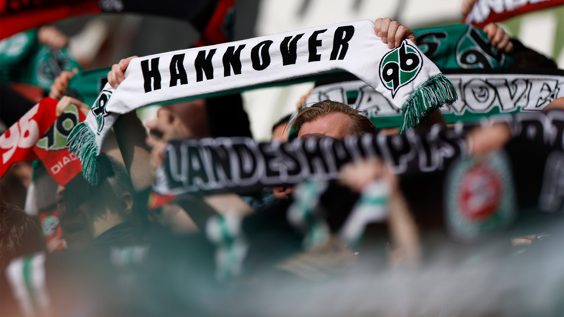Fans halten 96-Schals hoch, Gesichter sind nicht zu erkennen.