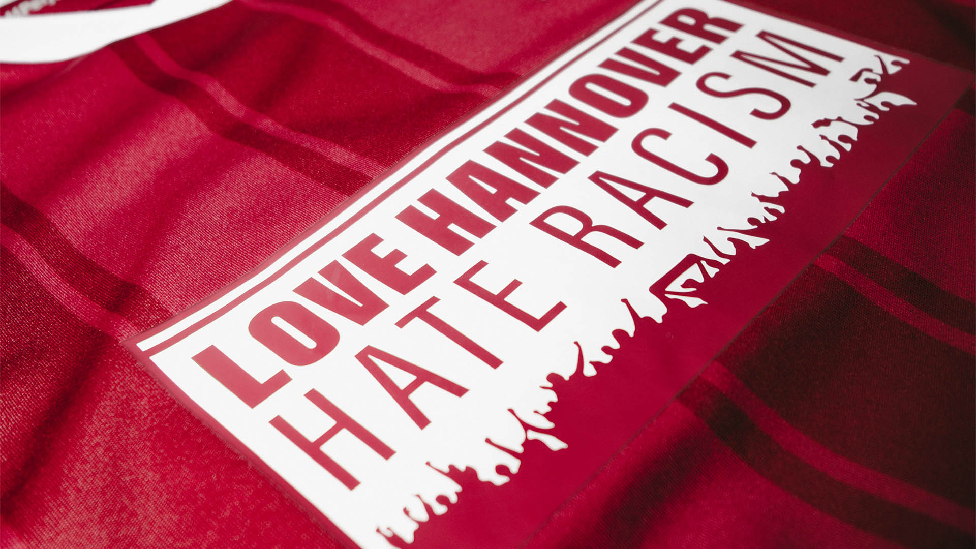 Detailaufnahme eines roten 96-Trikots, auf dem "Love Hannover, Hate Racism" steht.
