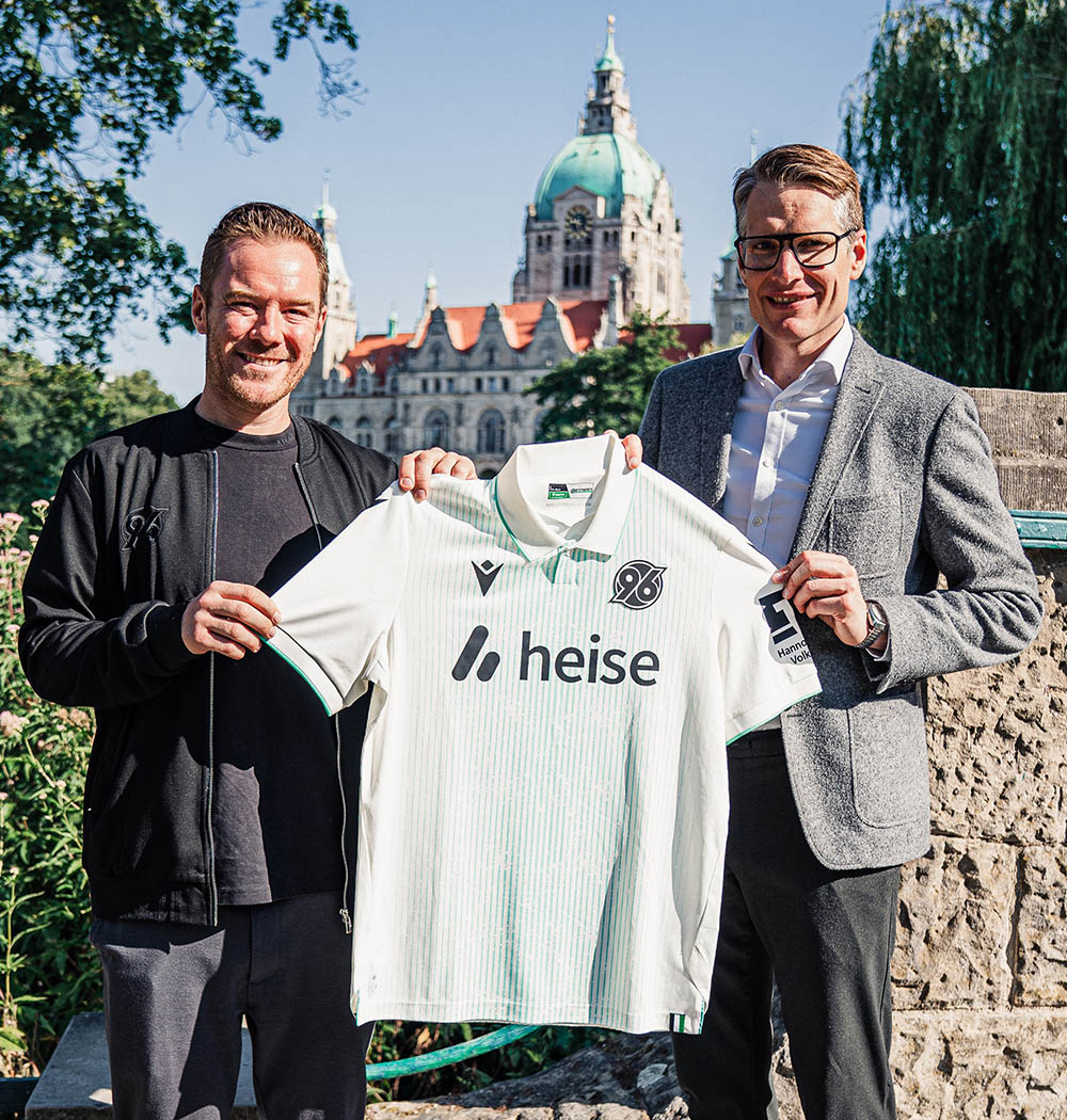 Zwei Personen halten das Ausweichtrikot hoch. Im Hintergrund das Neue Rathaus.