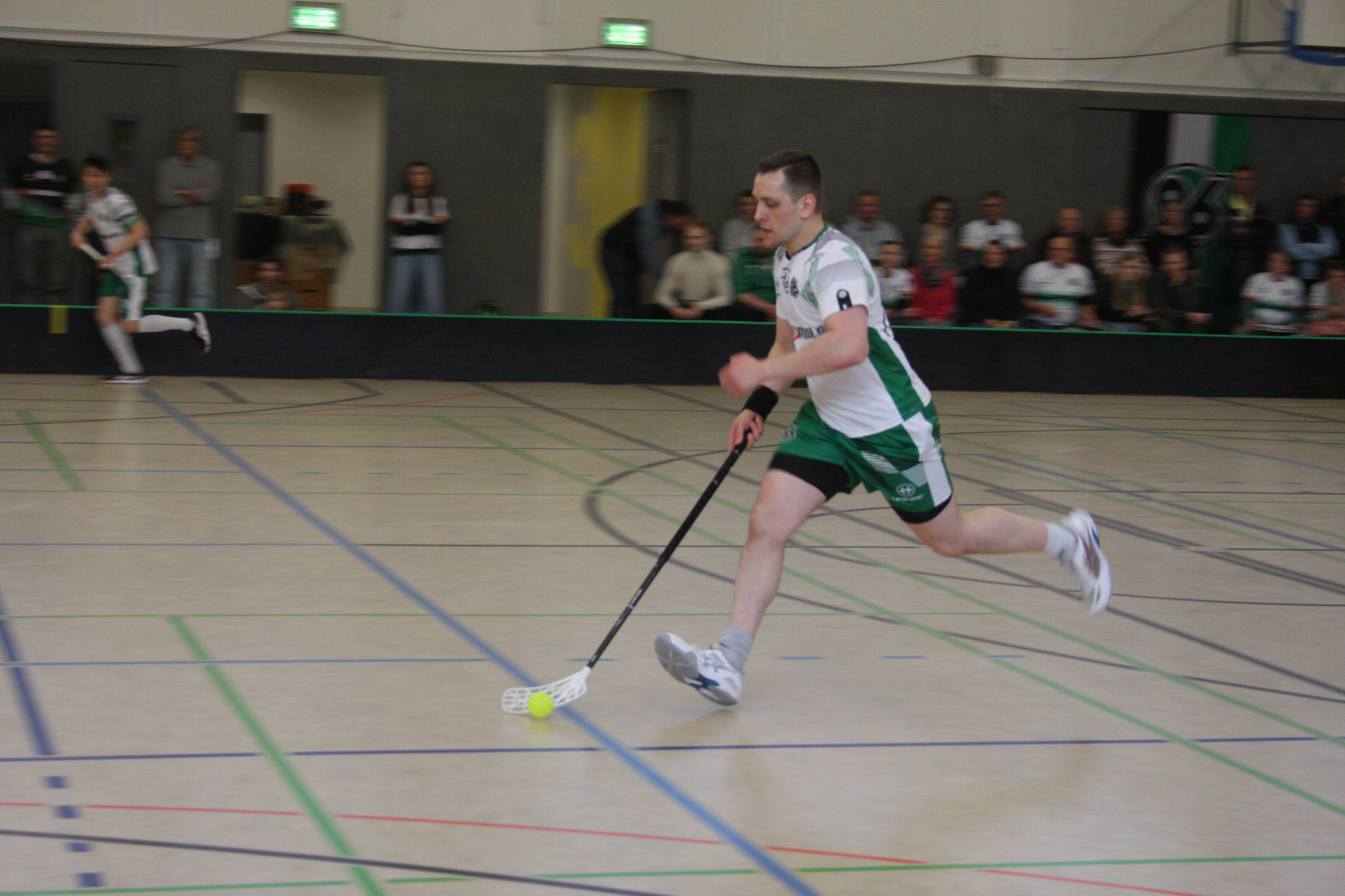 Floorball-Spieler Benedikt Stubbe von Hannover 96 läuft mit einem Floorball-Schläger im Trikot in einer Sporthalle