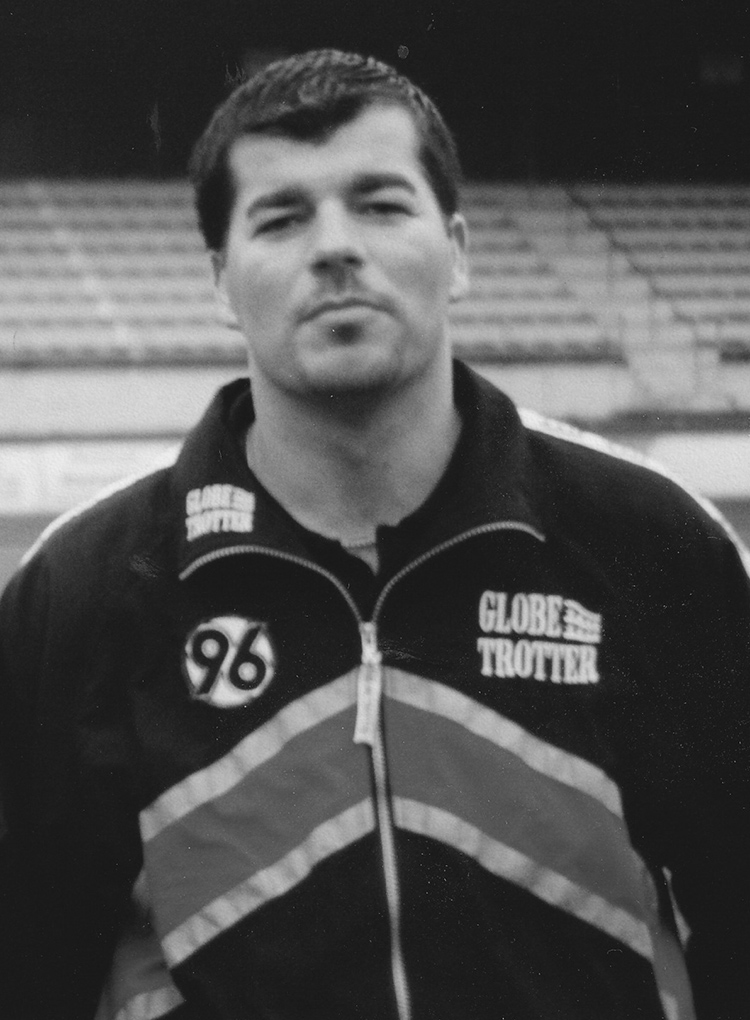 Schwarzweißbild von Carsten Beschorner in einer Hannover-96-Trainingsjacke.