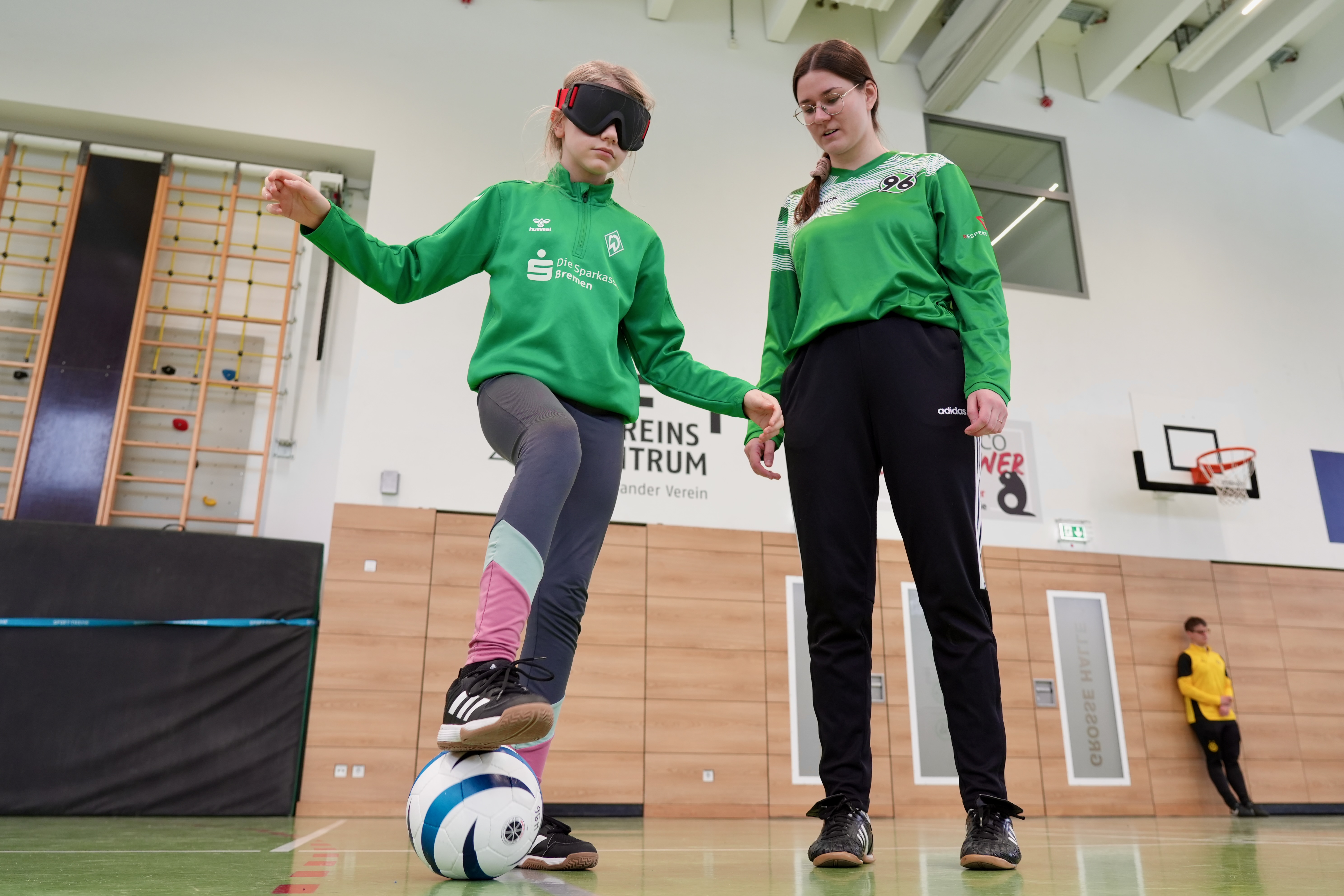 Ein Mädchen mit einer Dunkelbrille hält den Ball am Fuß.