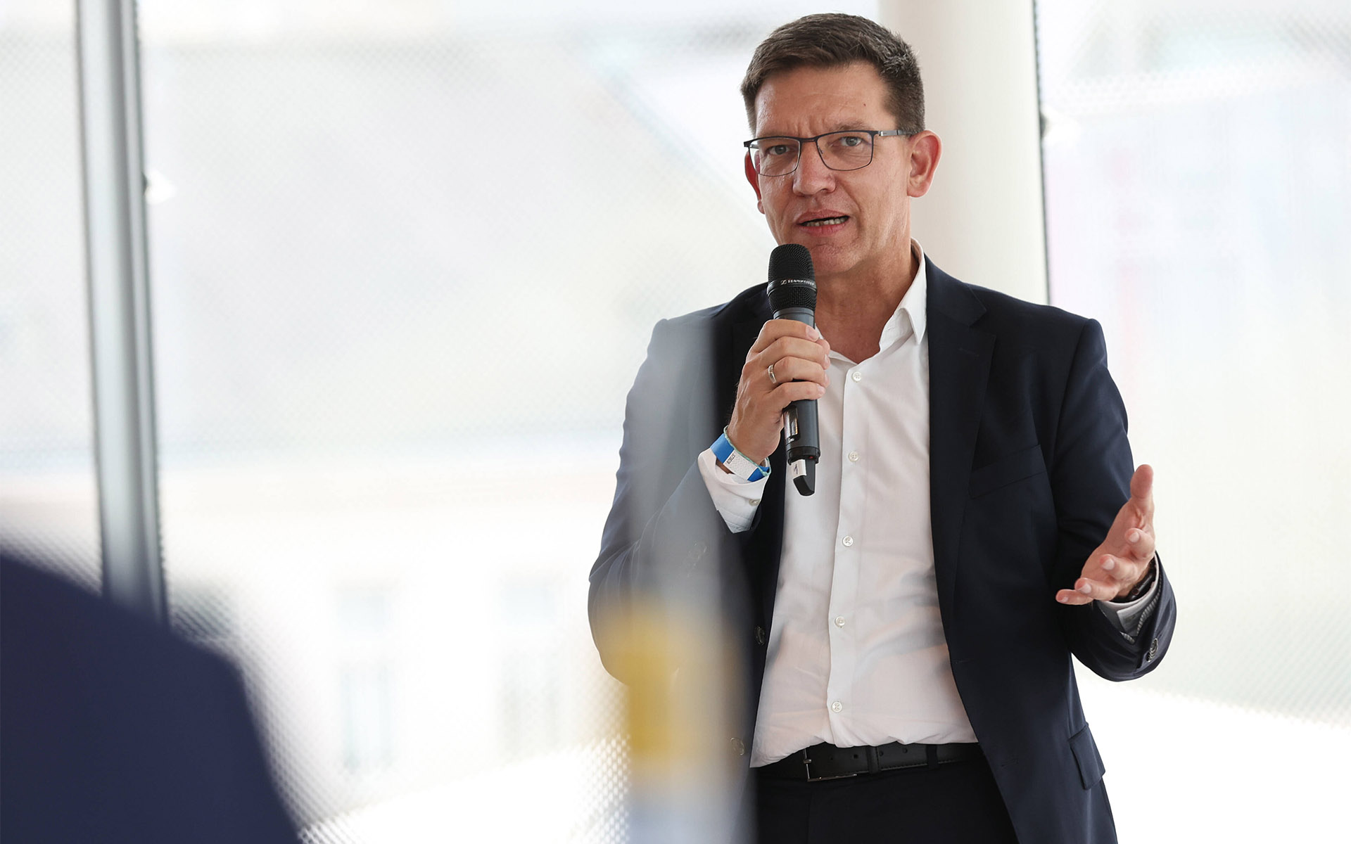 Björn Bremer im Anzug redet in ein Mikrofon. 