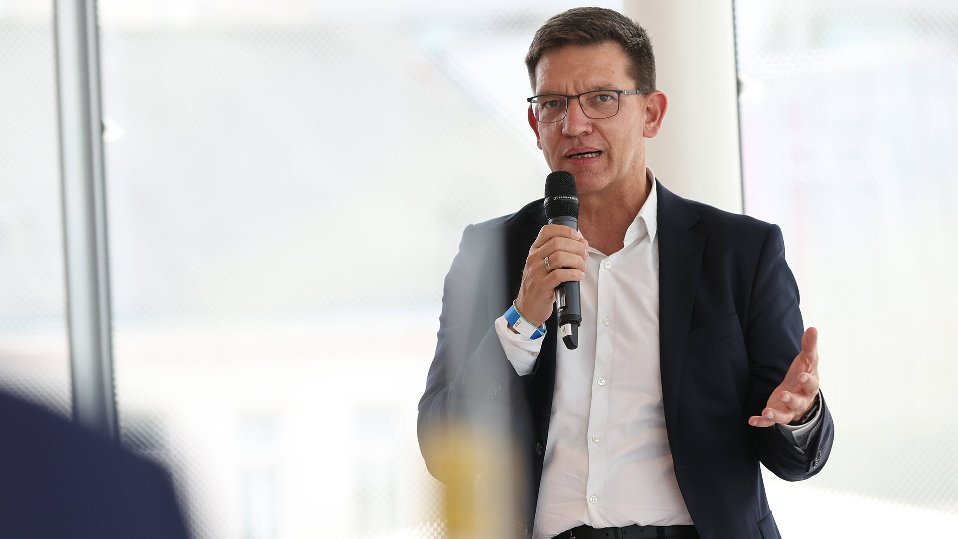 Björn Bremer im Anzug redet in ein Mikrofon. 