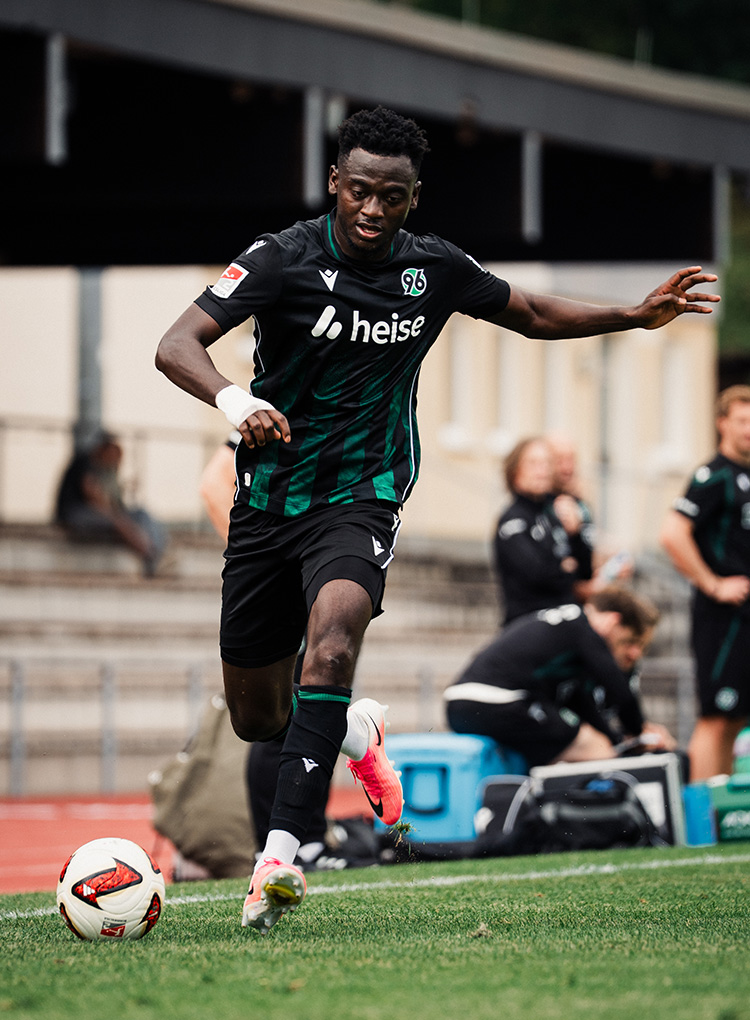 Der 96-Spieler Mustapha Bundu im Auswärtstrikot am Ball und mit einem Verband an der rechten Hand. 