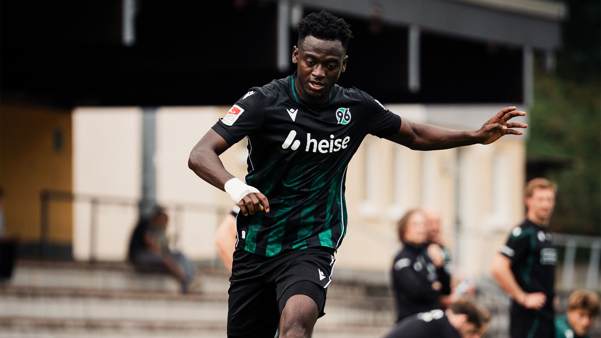 Der 96-Spieler Mustapha Bundu im Auswärtstrikot am Ball und mit einem Verband an der rechten Hand. 