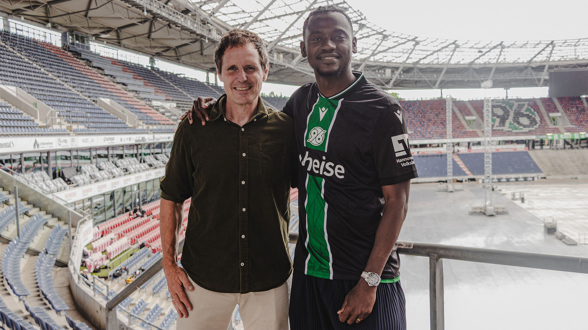 Hannover-96-Neuzugang Mustapha Bundu steht Arm in Arm mit seinem Schwiegervater Flemming Povlsen im Stadion. 