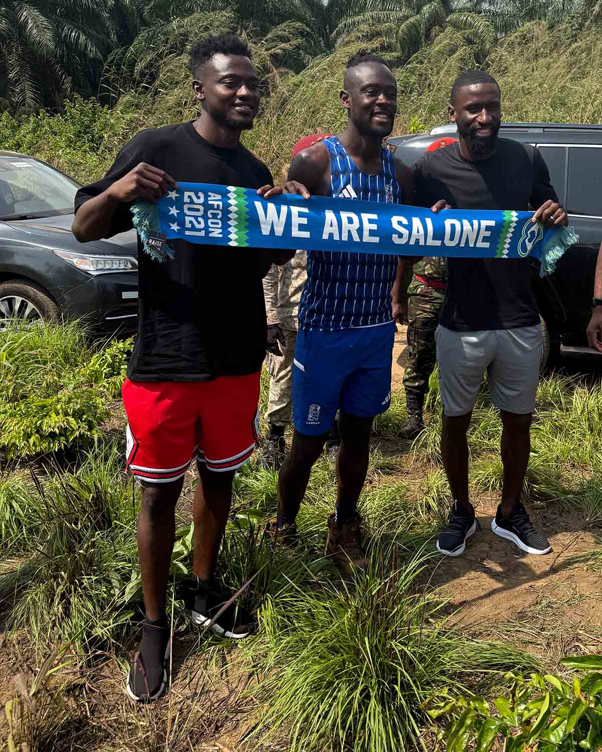 Bundu, Rüdiger und ein gemeinsamer Freund halten einen Sierra-Leone-Schal hoch.