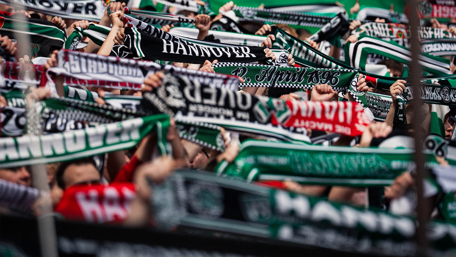 96-Fans halten Schals hoch, Gesichter sind nicht zu erkennen.