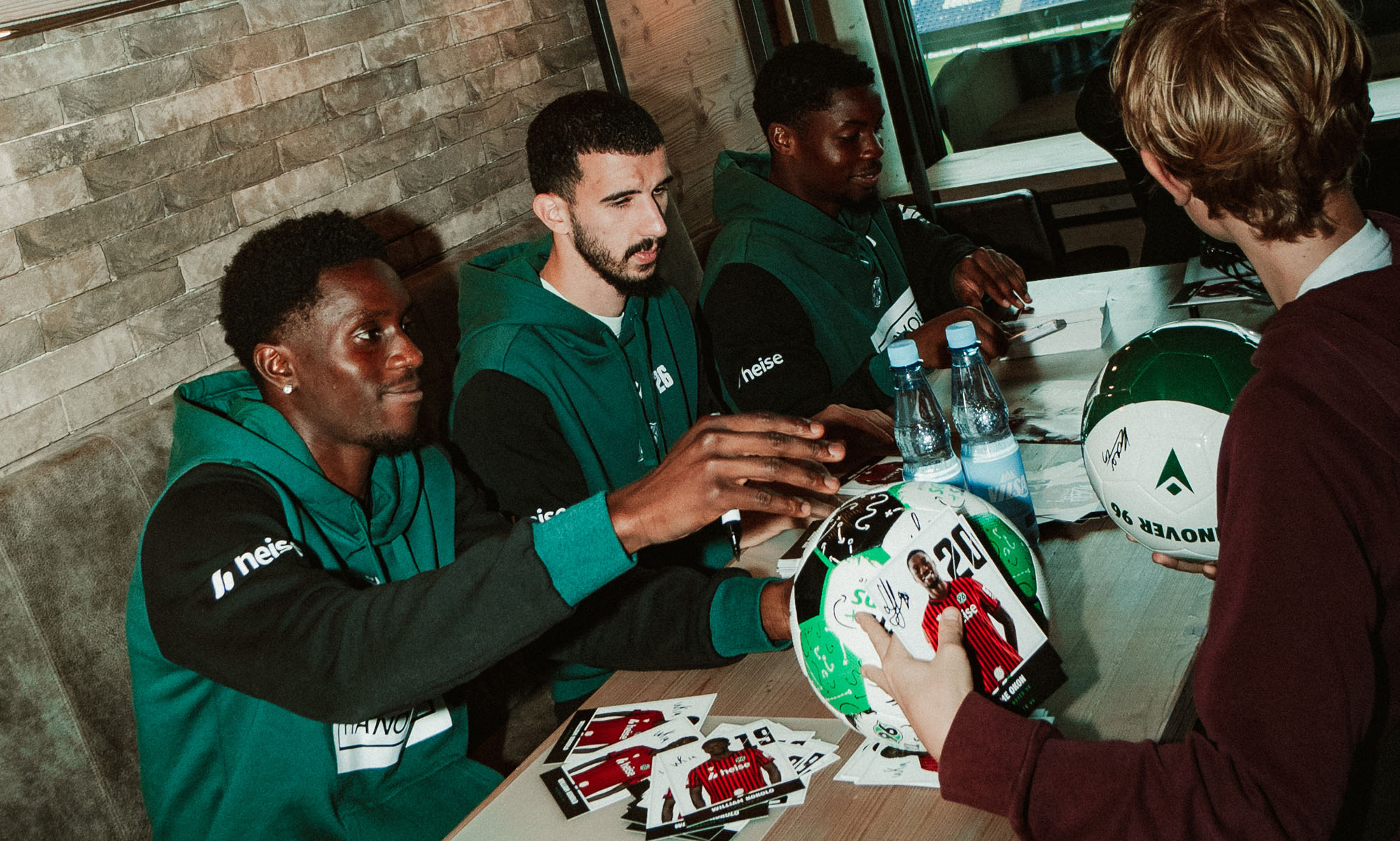 William Kokolo, Waniss Taibi und Ime Okon schreiben Autogramme.