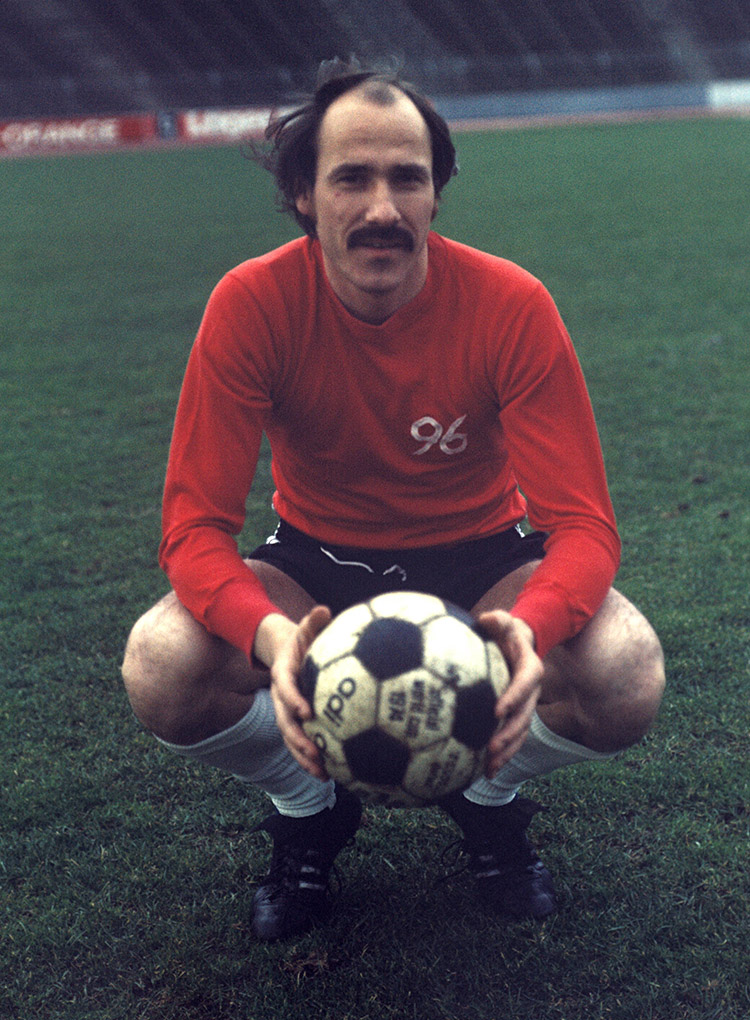 Georg Damjanoff hockt im Trikot und hält einen Fußball in der Hand.