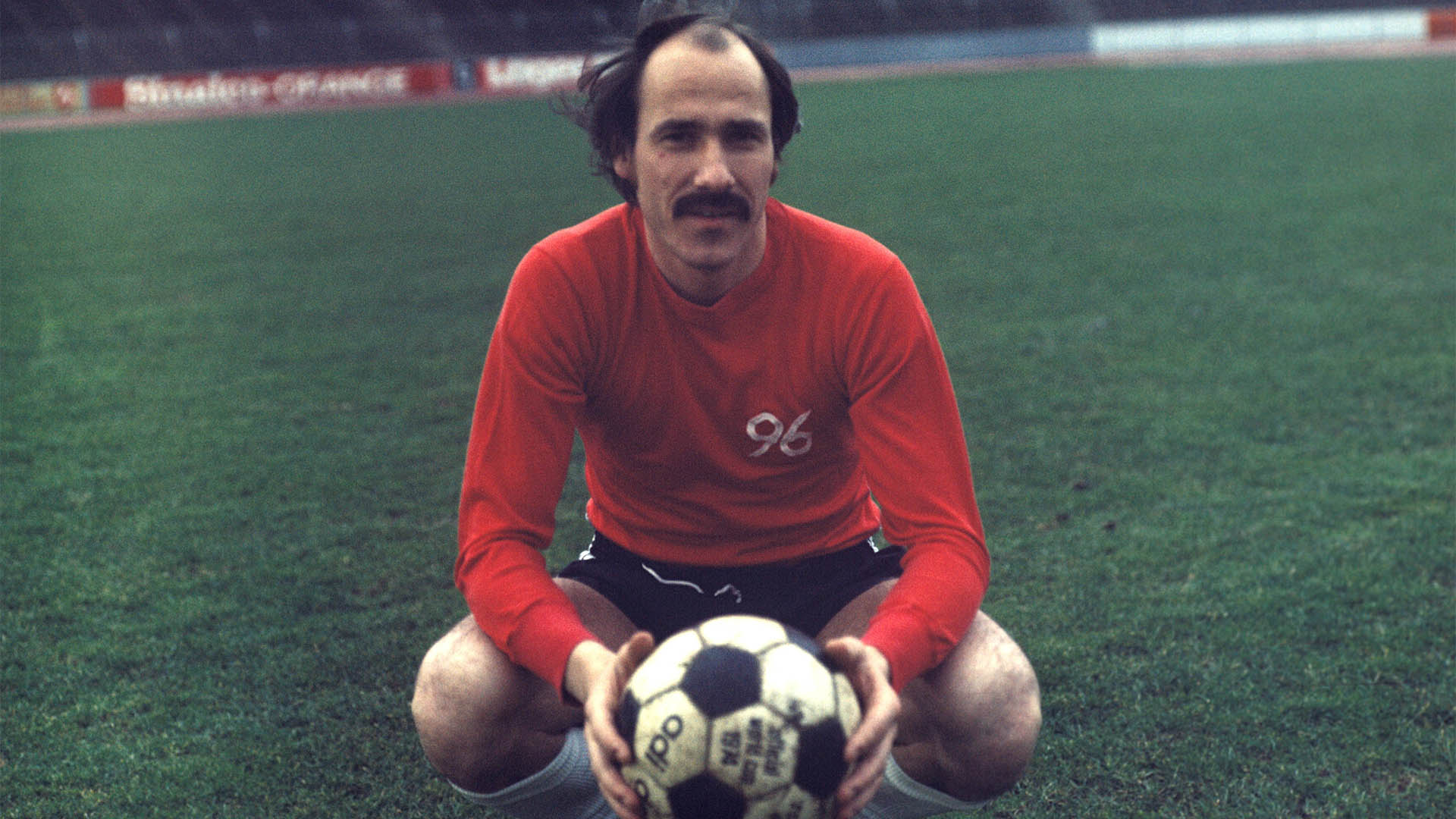 Georg Damjanoff hockt im Trikot und hält einen Fußball in der Hand.