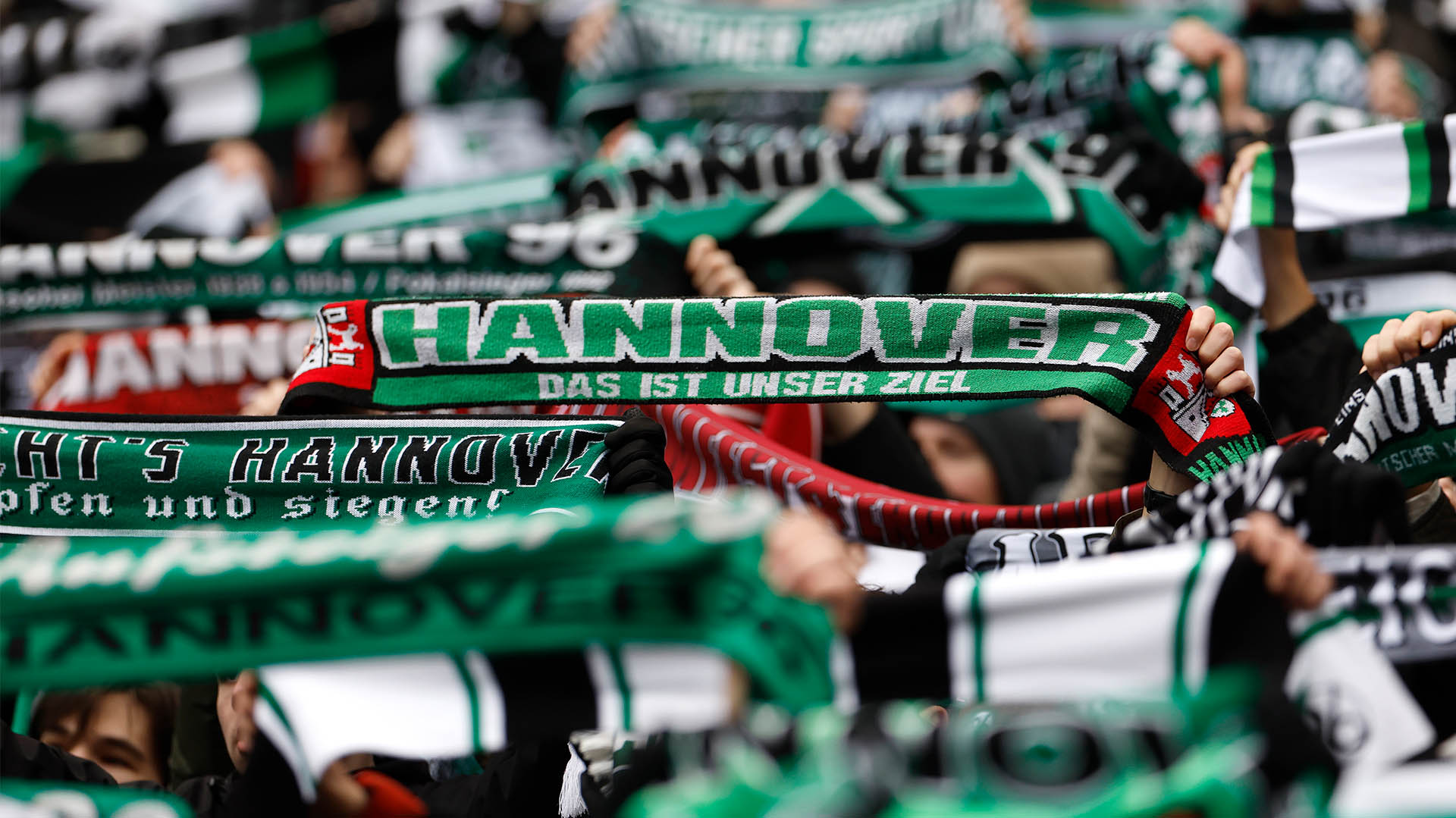 96-Schals werden in die Höhe gehalten, Gesichter sind nicht zu erkennen.