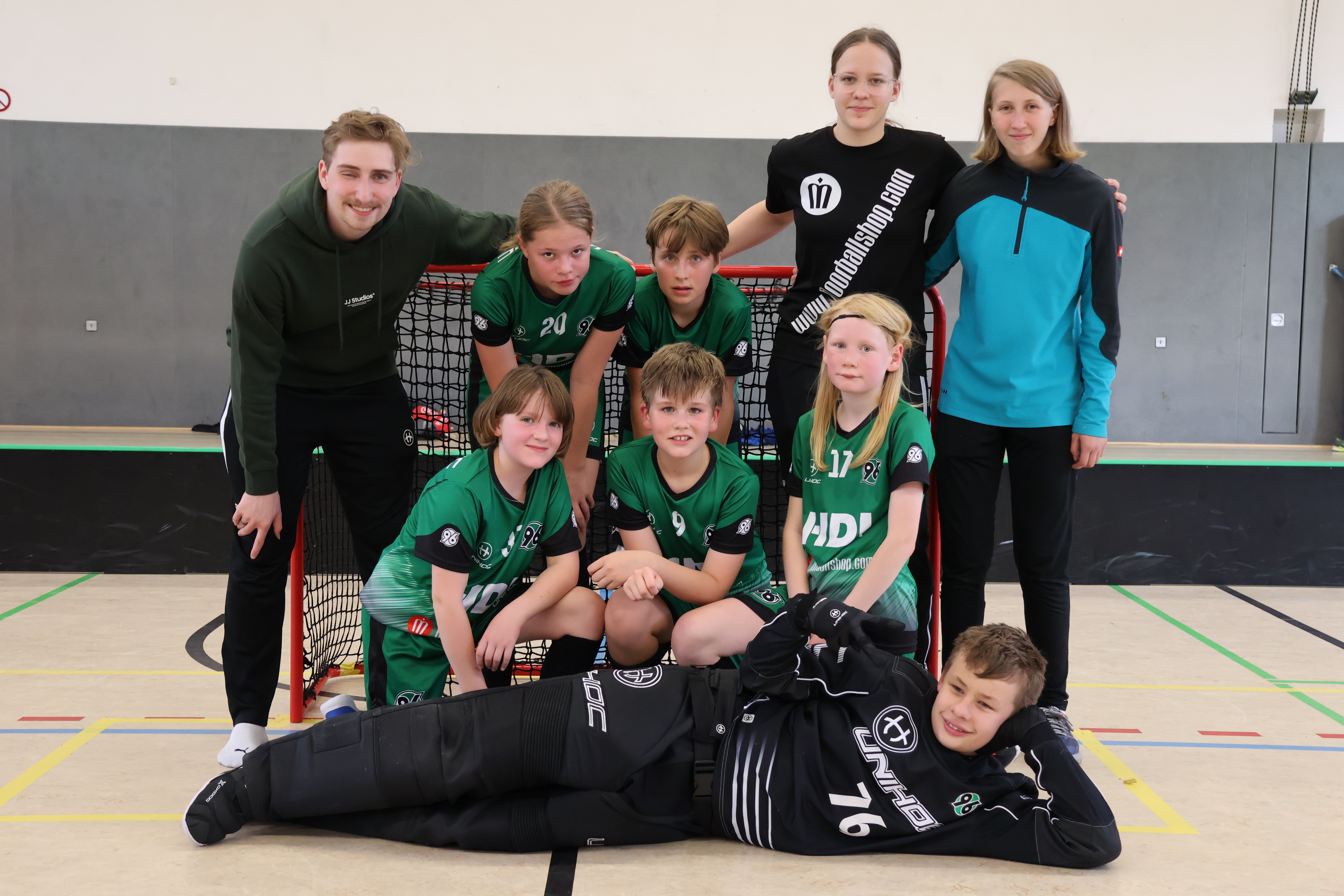 Die U13-Mannschaft steht vor einem Floorballtor und machen ein Mannschaftsfoto.