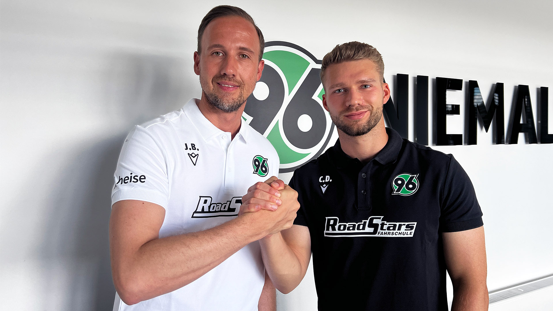 Julian Battmer und Clemens Döring beim Handshake, im Hintergrund ist das 96-Logo vor einer weißen Wand.