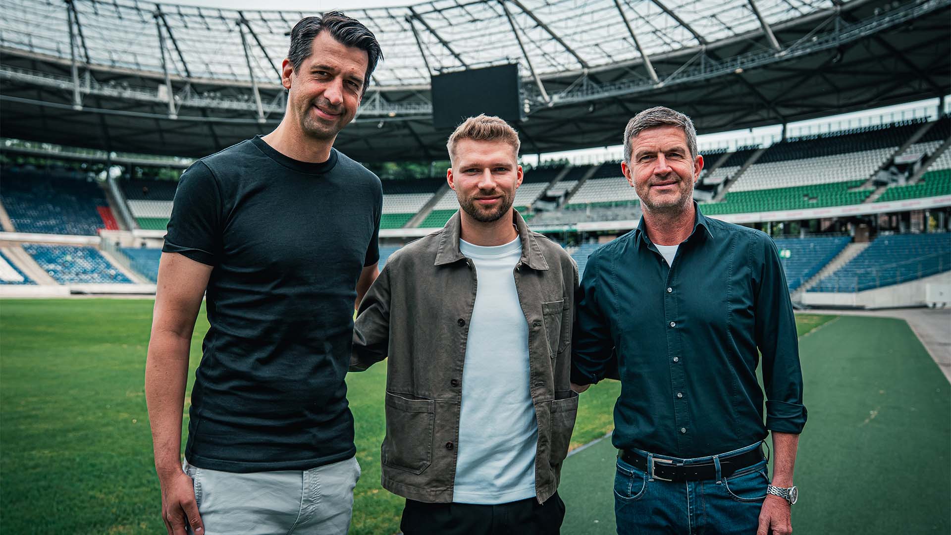 Jonas Boldt, Clemens Döring und Ralf Becker stehen im leeren Stadion, im Hintergrund die neuen schwarz-weiß-grünen Sitze.