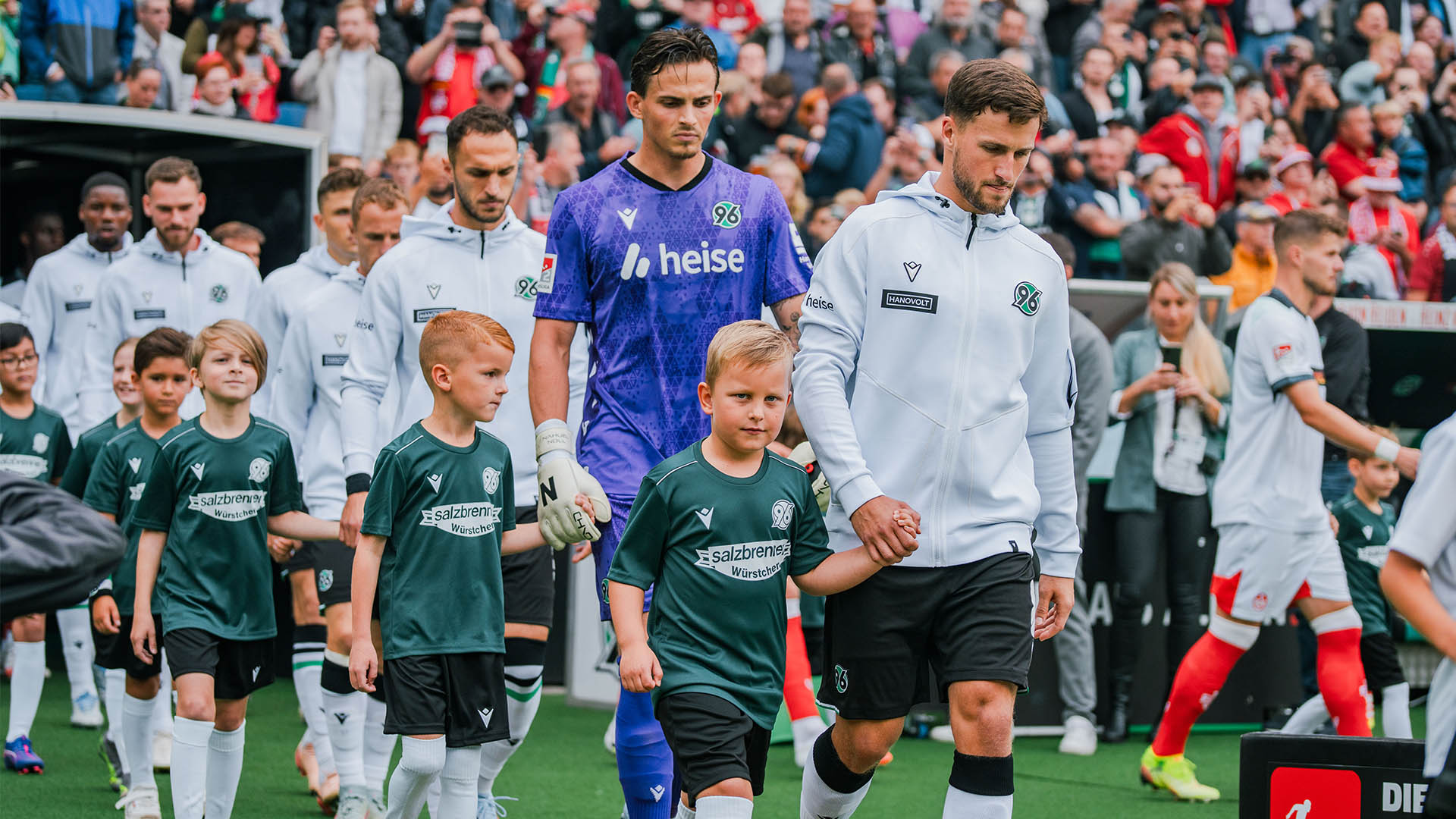 Kinder an der Hand von Fußball-Profis beim Einlaufen ins Stadion.