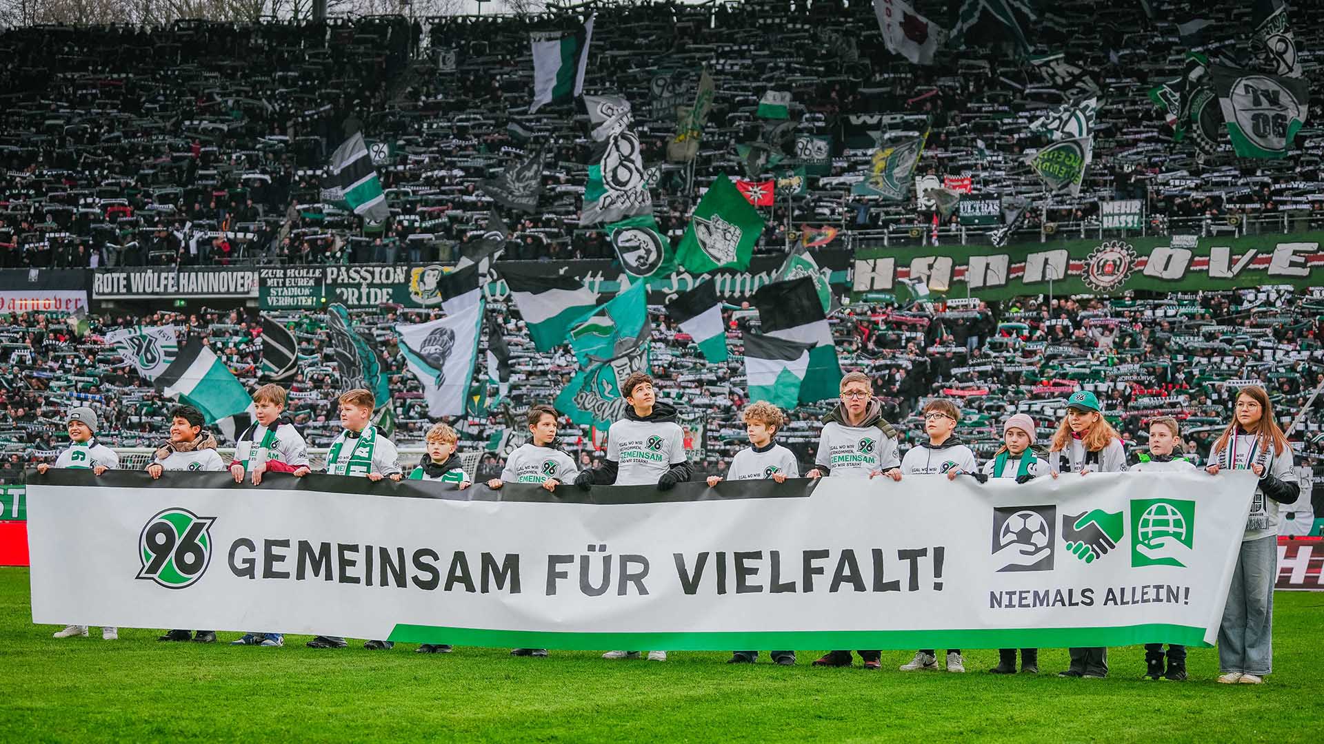 Kinder halten bei einem Fußballspiel einen Banner.