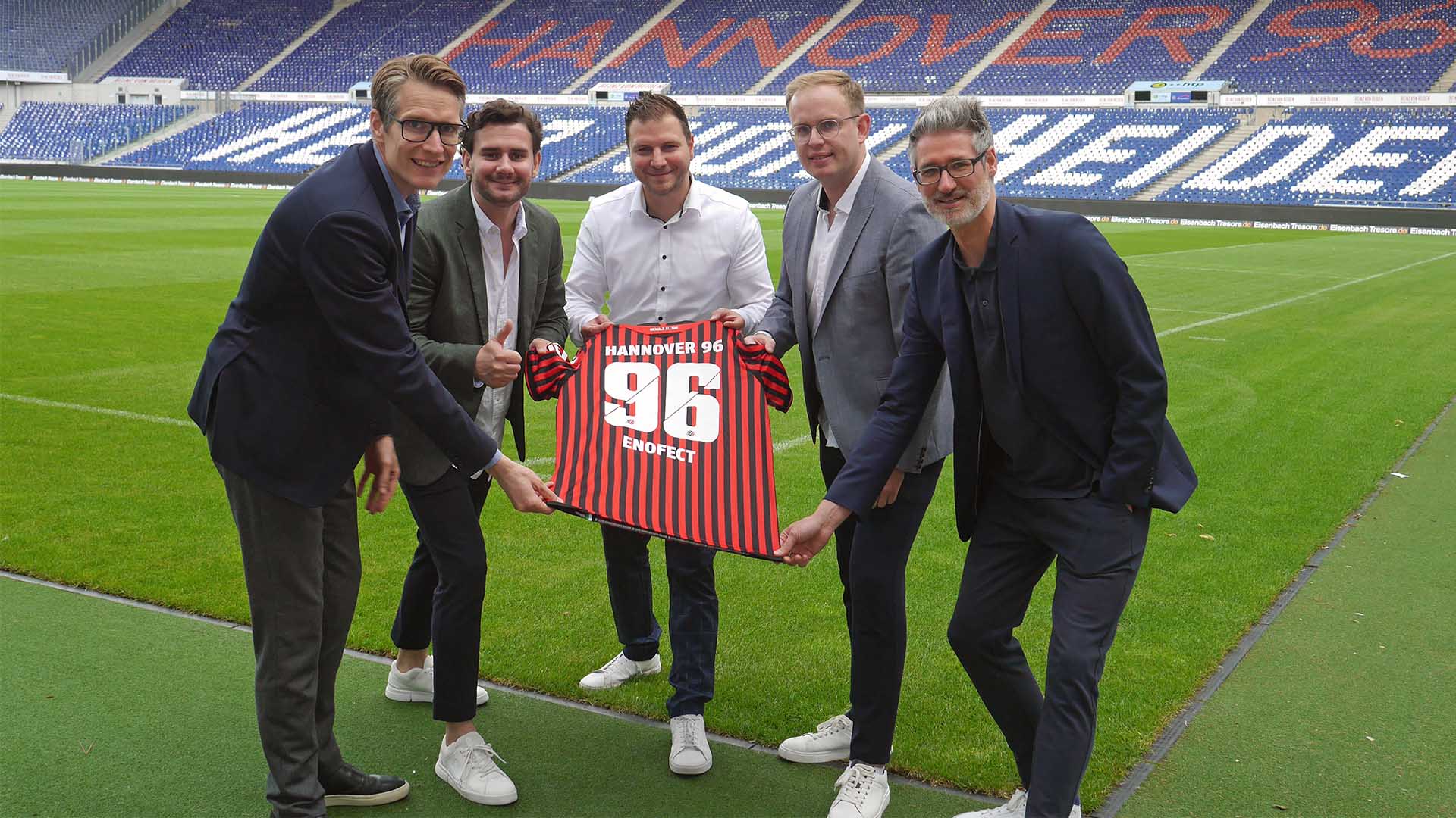 Fünf Verantwortliche von Hannover 96, Enofect und Sportfive halten ein 96-Trikot mit dem Flock 96 und Enofect in der Heinz von Heiden Arena.