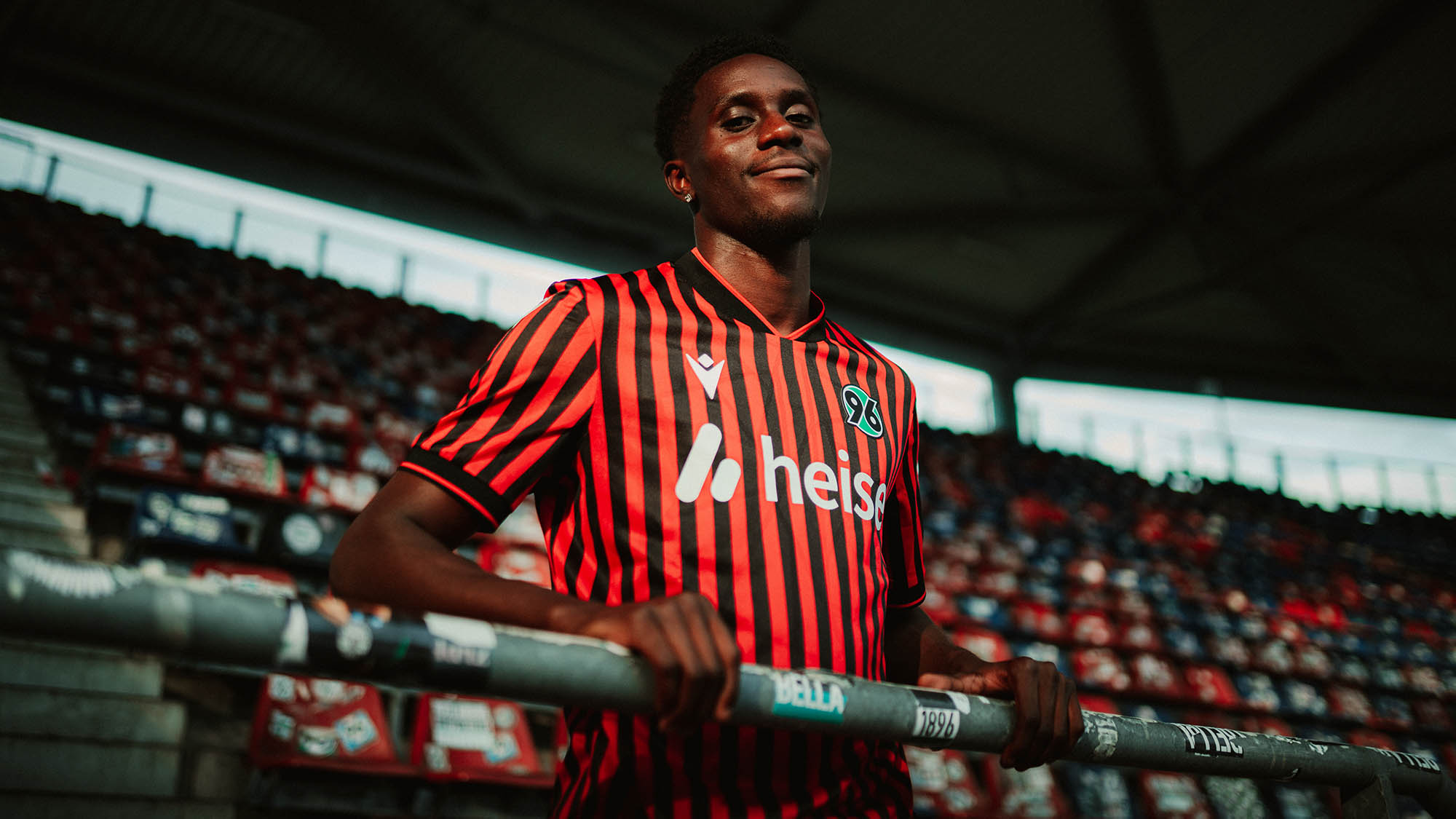 William Kokolo steht im 96-Trikot auf der Tribüne des Stadions.