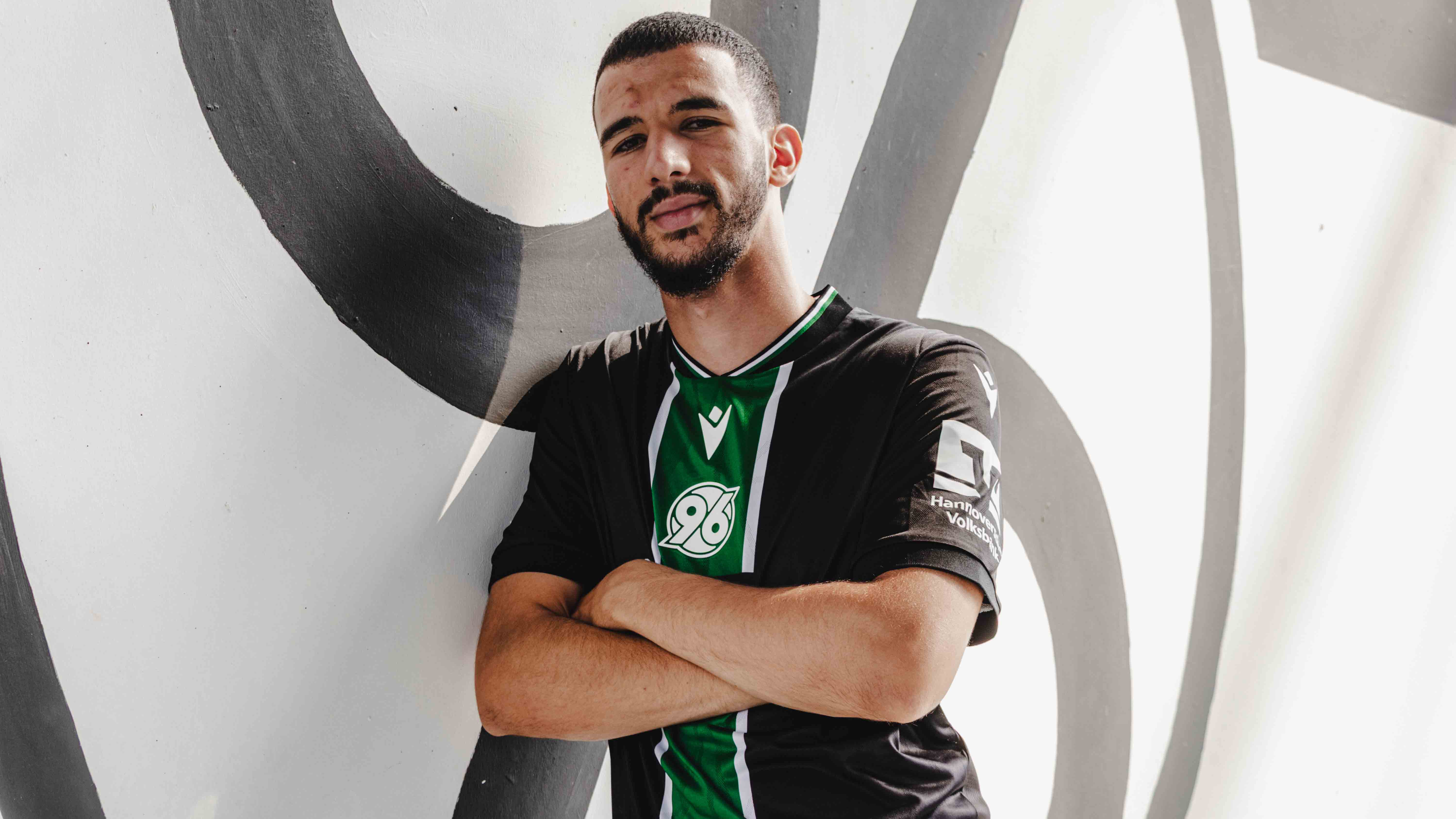 Hannover-96-Neuzugang Waniss Taibi lehnt mit der rechten Schulter an einer Wand in der Heinz von Heiden Arena.