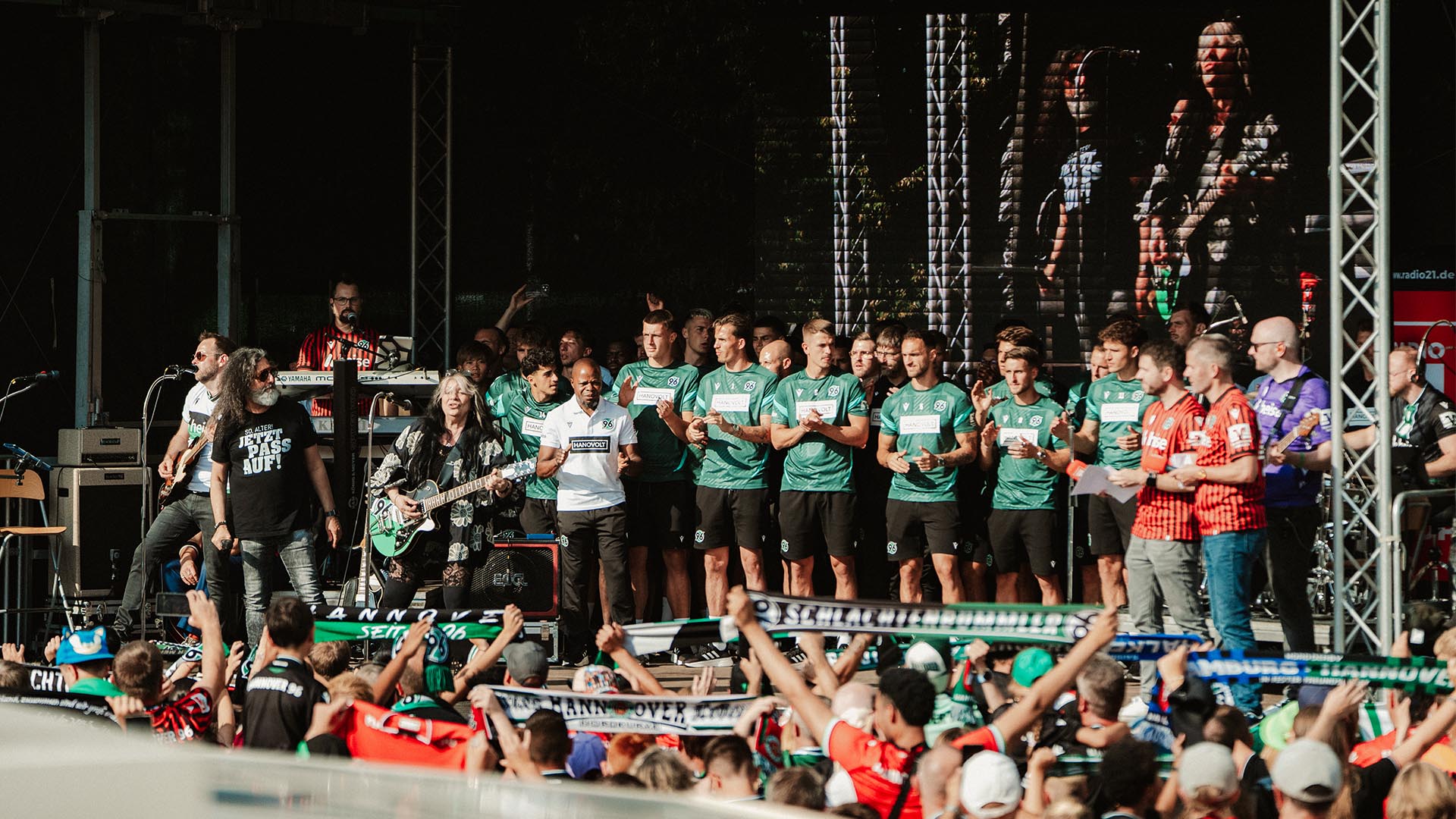 Die 96-Mannschaft steht auf der Bühne und singt mit Anca und Ossy, Fans davor schwenken Schals.