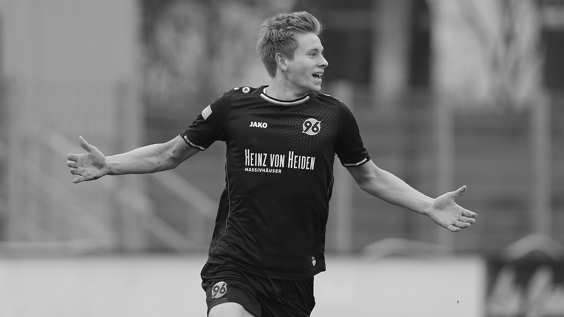 Schwarz-Weiß-Aufnahme von Niklas Feierabend im 96-Trikot, der die Arme zur Seite ausbreitet.