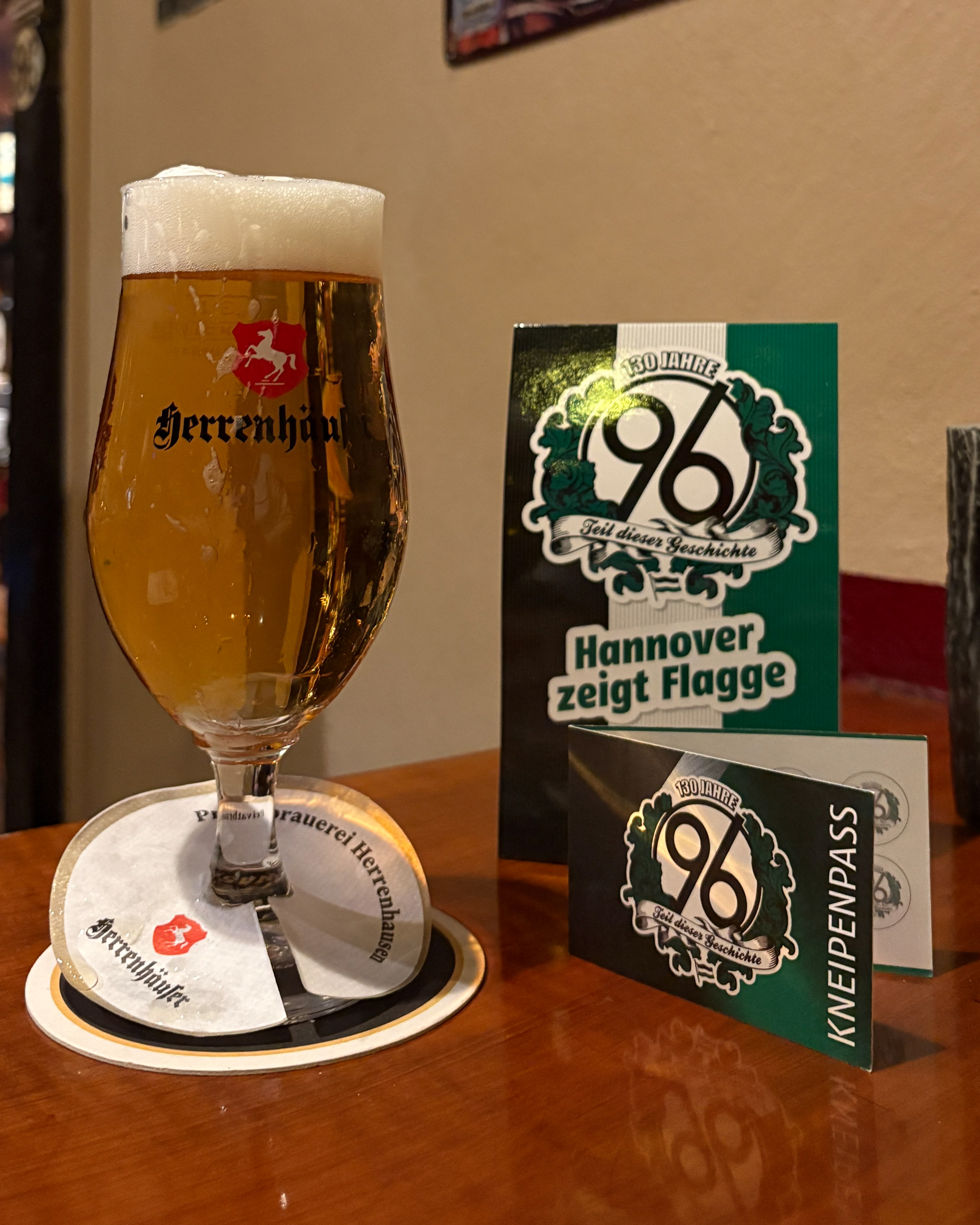 Links im Bild sieht man ein großes Glas Bier und rechts daneben befindet sich der 96 Kneipenpass.