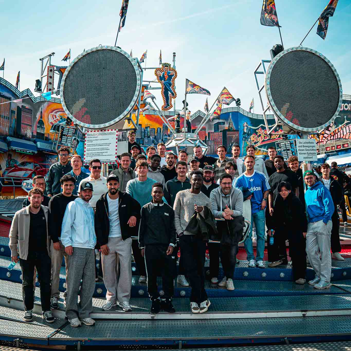 Das 96-Team posiert vor einer Achterbahn.