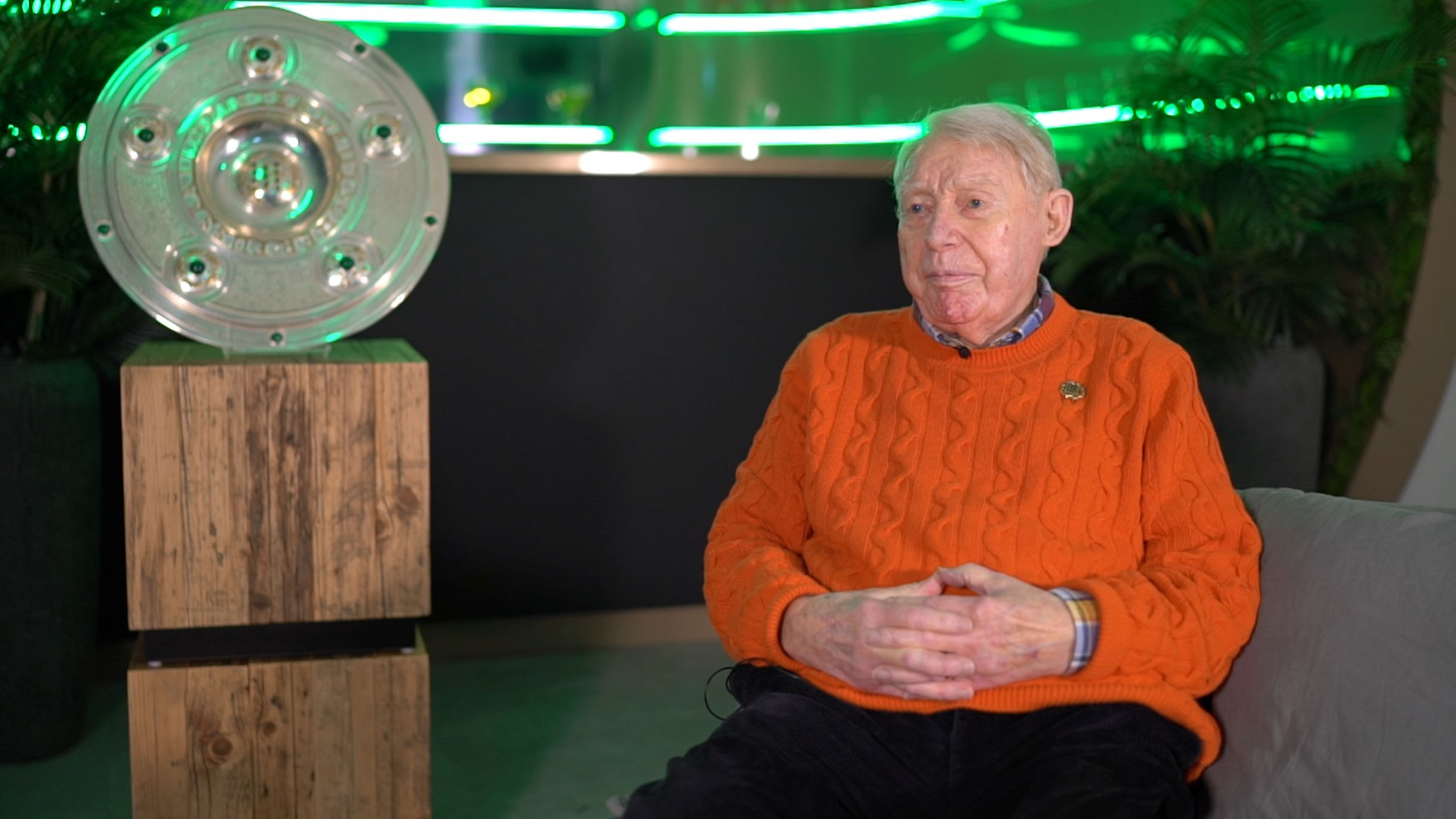 Rolf Gehrcke sitzt neben der Meisterschale.