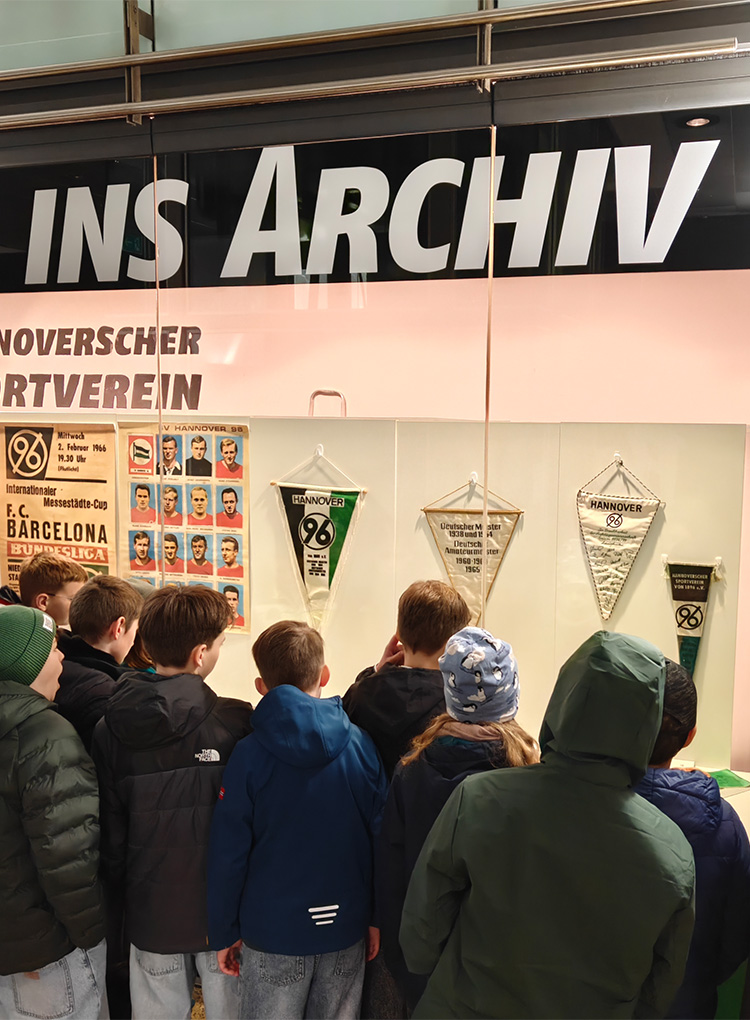 Die Kinder schauen Exponate in einem Schaufenster an.