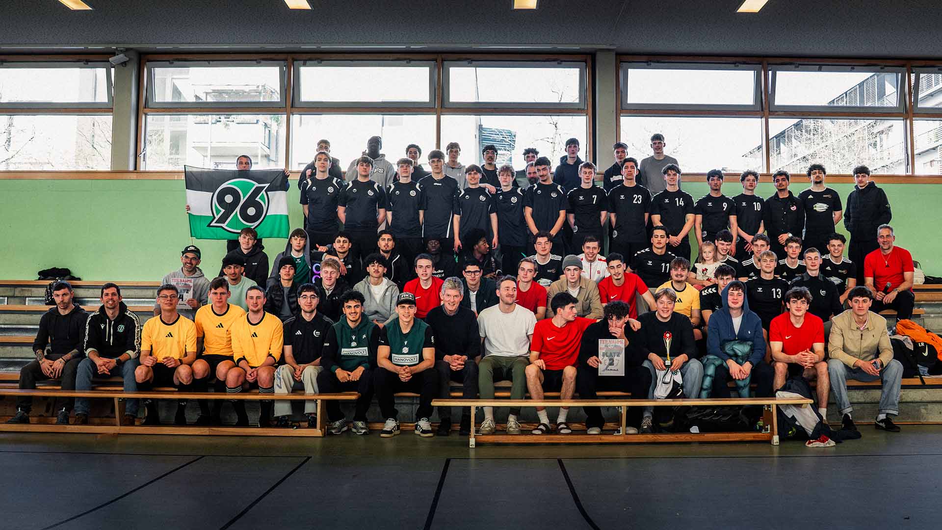 Alle Teilnehmerinnen und Teilnehmer des Turnies posieren mit den zwei 96-Profis für ein Gruppenbild.