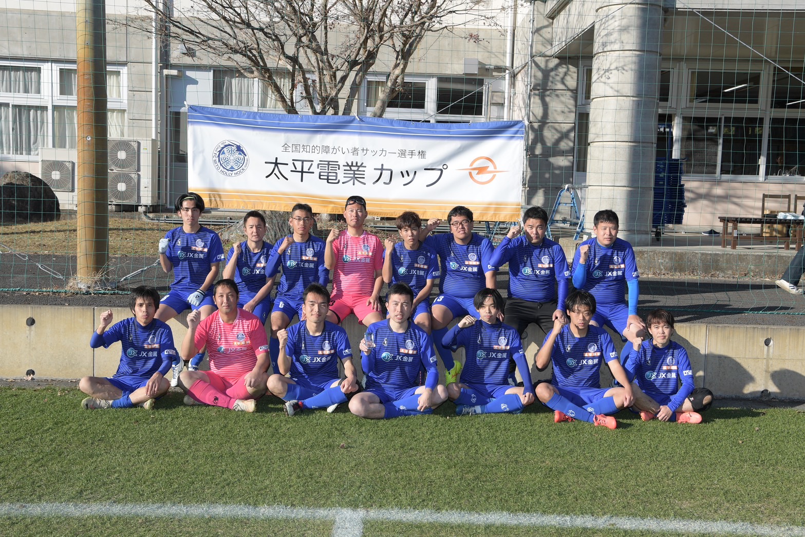 Die Handicapfußballer des FC Mito Hollyhock mit dem Banner ihres Hauptsponsors TAIHEI DENGYO.