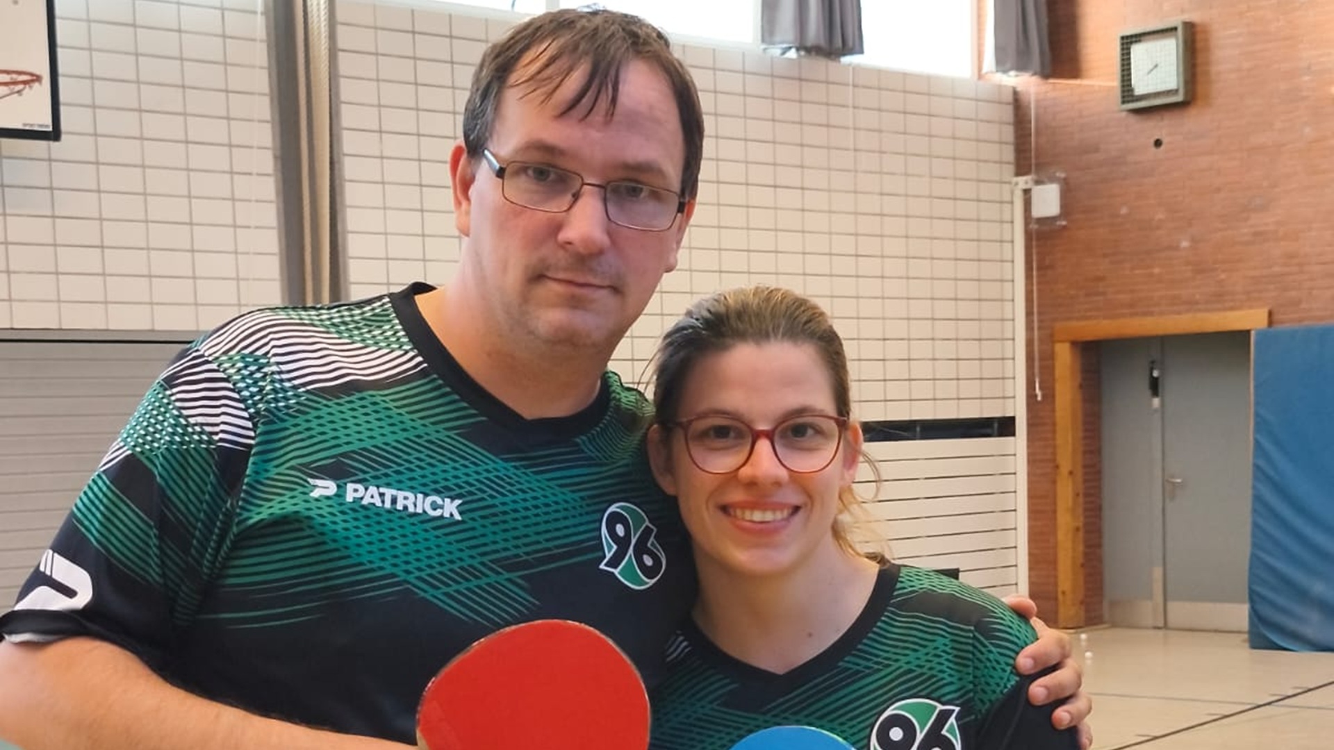 Norman Lindner und Franzsika Sieber aus der Abteilung Handicapsport von Hannover 96 in Trikots und mit Tischtennis-Schlägern