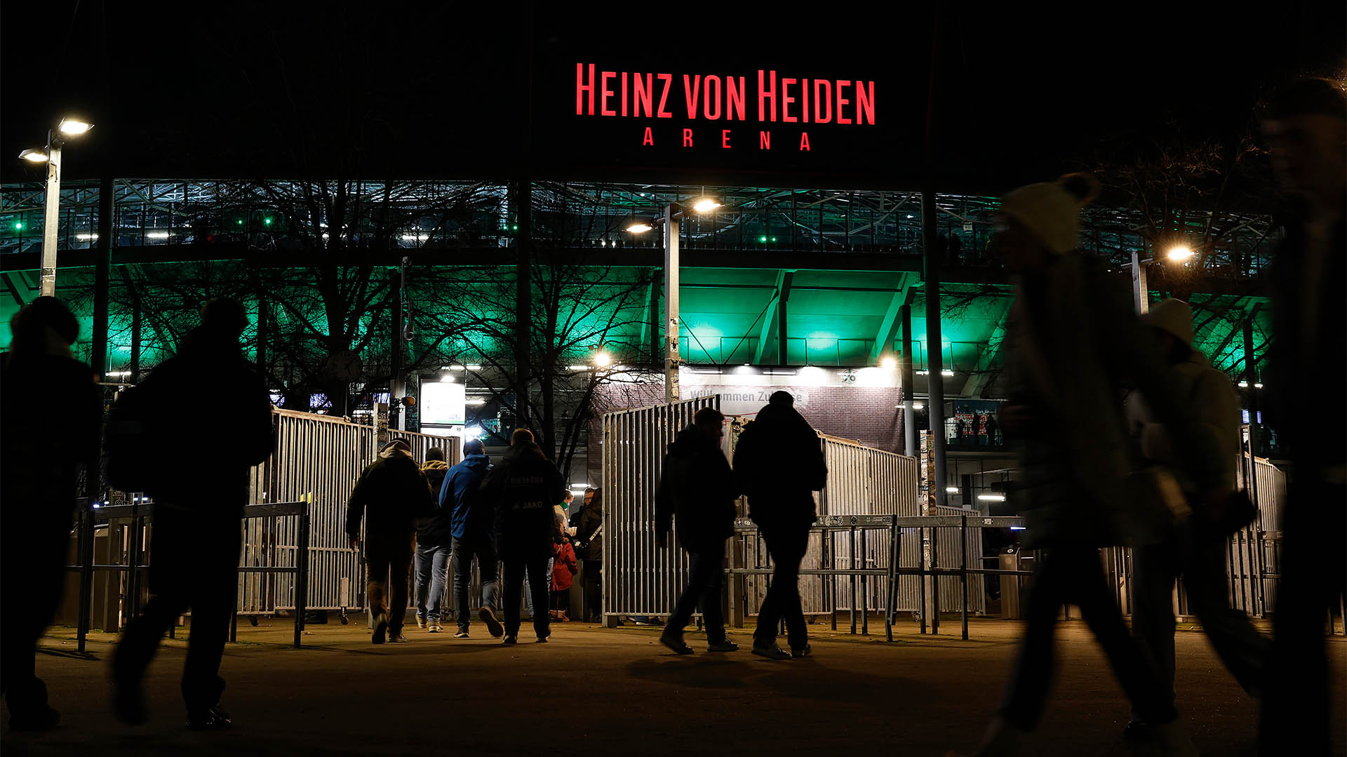 Personen betreten das Stadion über den Nordeingang im Dunkeln. Das Stadion leuchtet.
