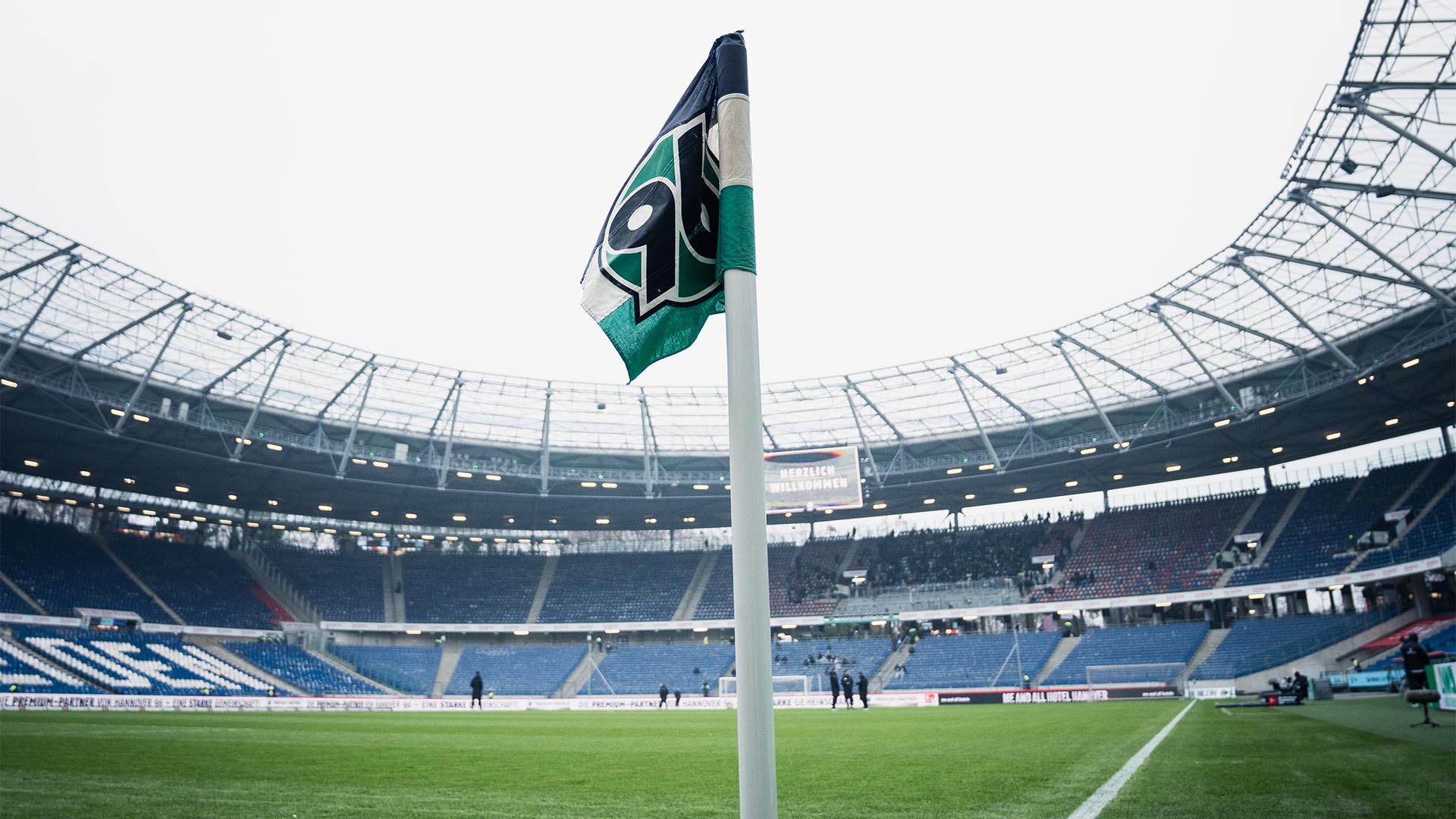 Blick in die fast leere Heinz von Heiden Arena, die Eckfahne im Vordergrund. Auf der Videowall steht "Herzlich willkommen".