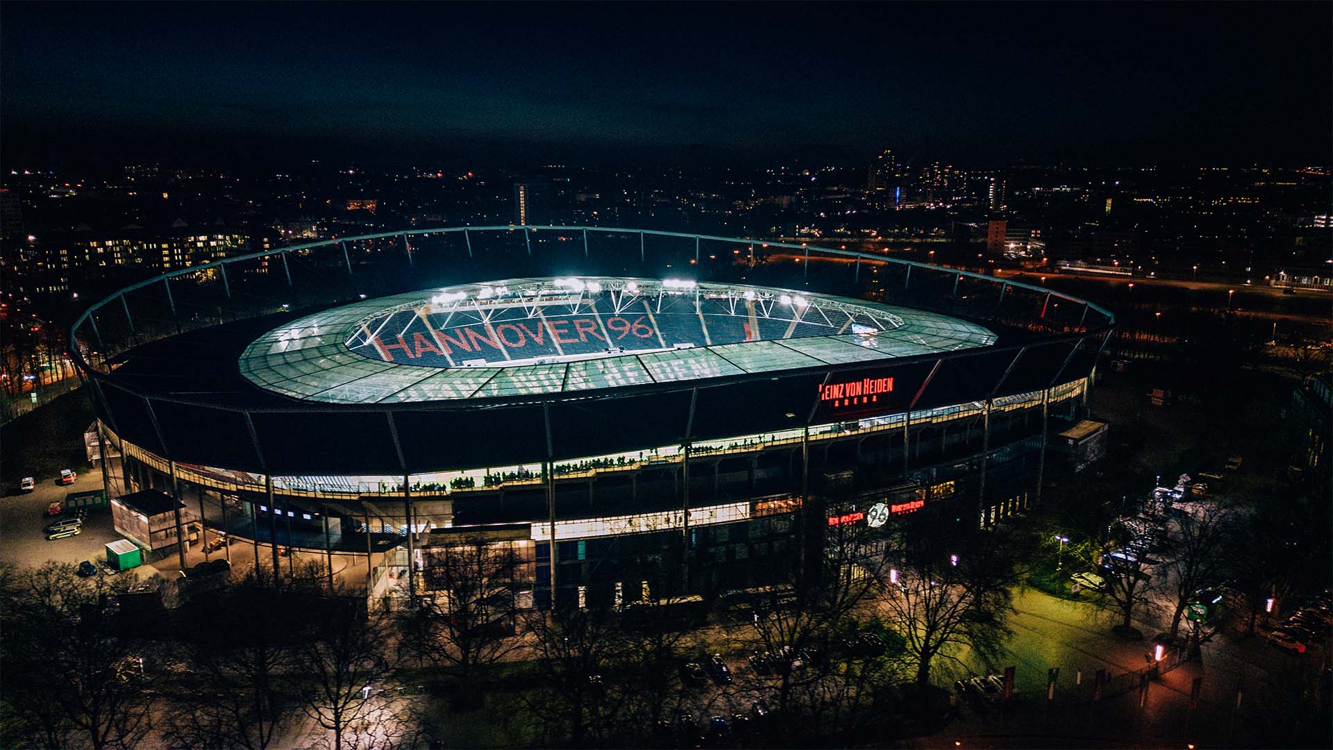Luftaufnahme von der hell erleuchteten Heinz von Heiden Arena im Dunkeln.
