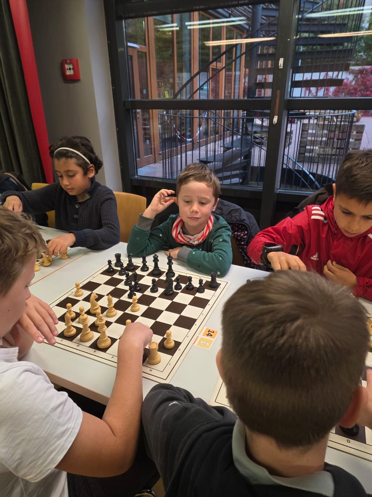 Mehrere Kinder sitzen an einem Tisch und spielen Schach.
