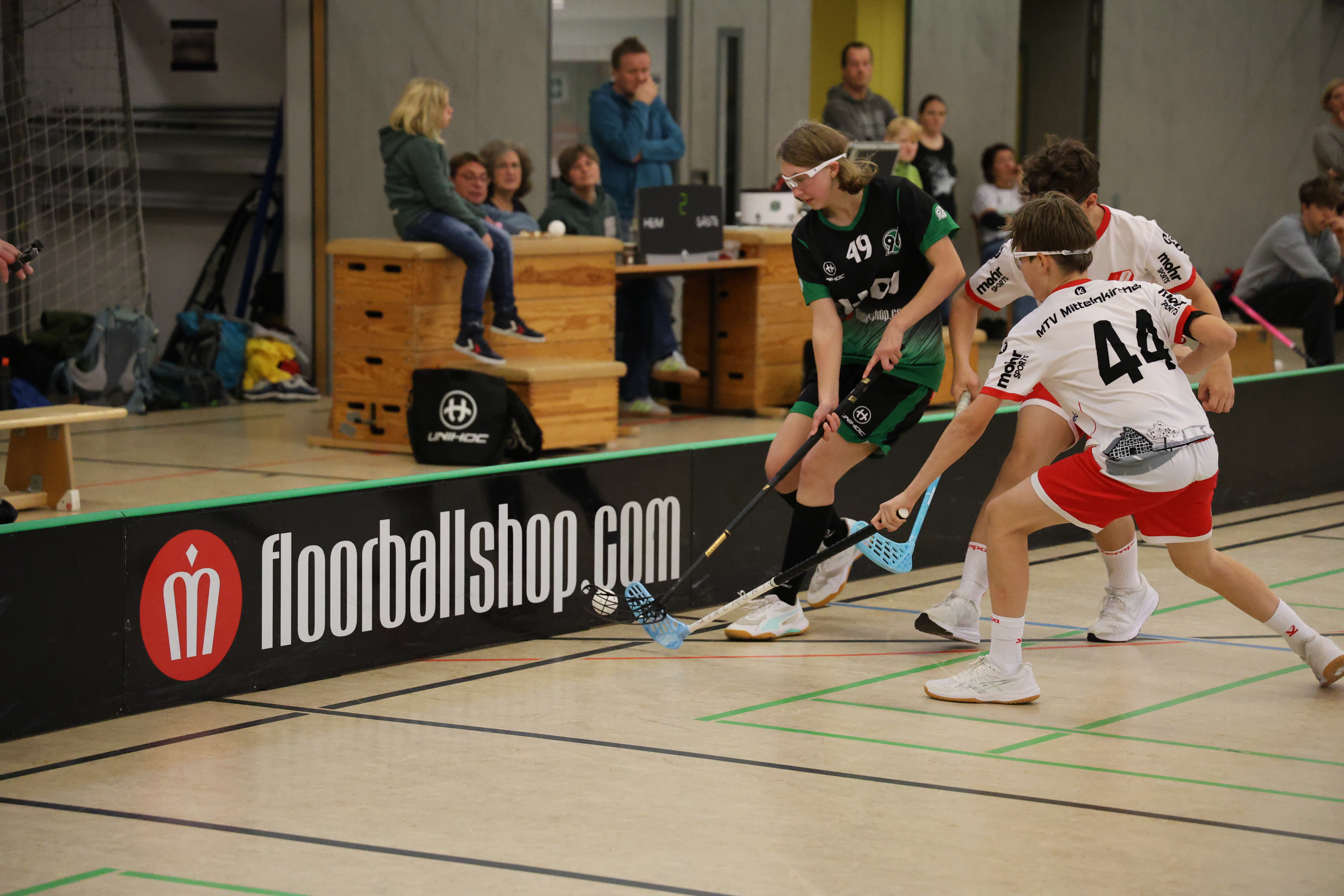 Drei SpielerInnen im Zweikampf um den Ball.