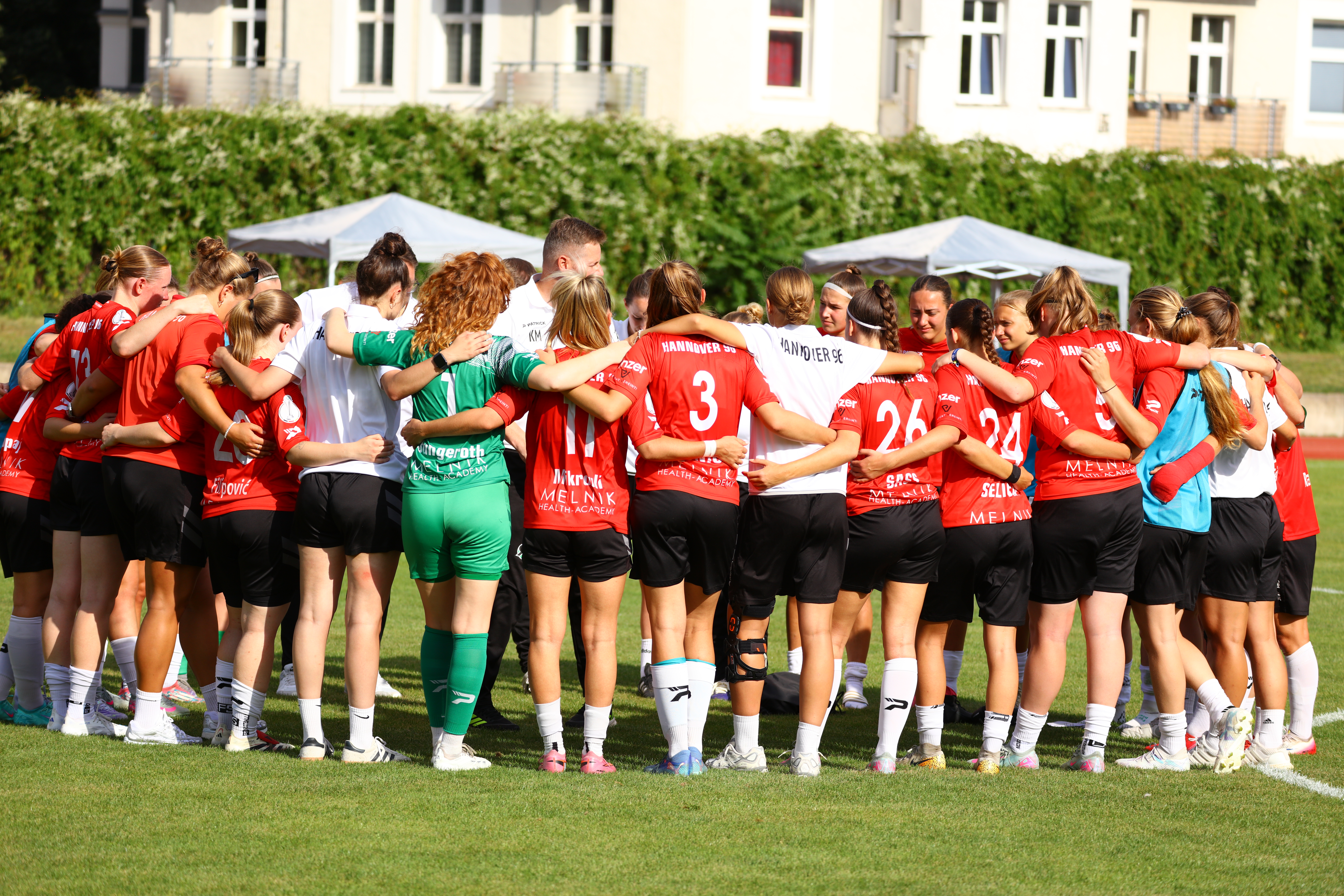 Die Frauenmannschaft steht Arm in Arm in einem Kreis zusammen.